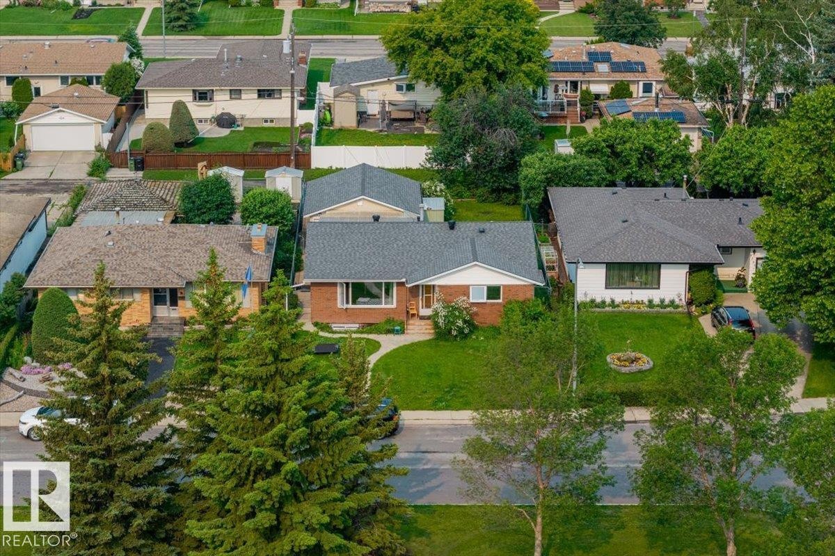 Traditional brick exterior featuring a grey shingle roof, established front lawn, and paved driveway - 8736 72 Street Nw, Edmonton, AB - Outdoor
