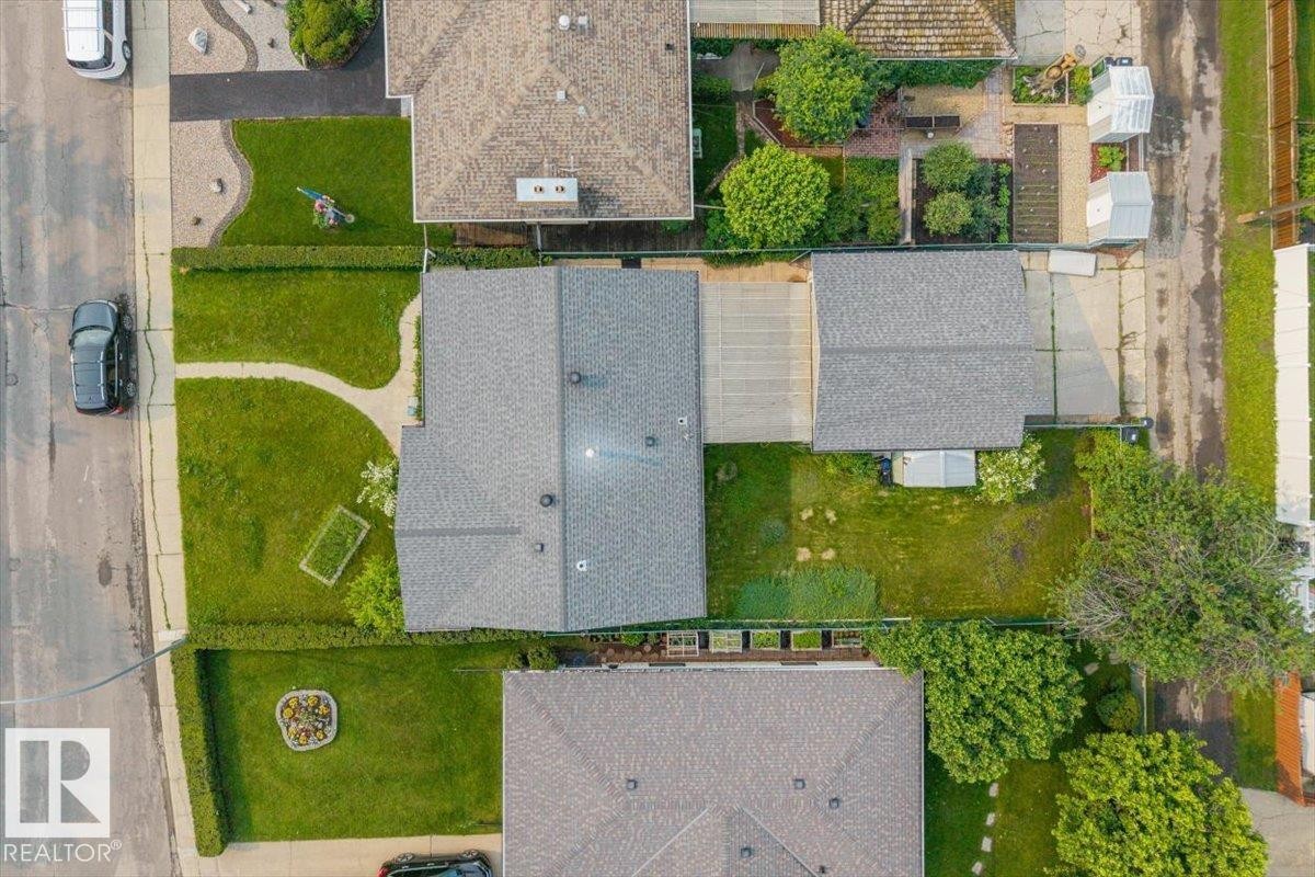 Aerial perspective showcasing a property with a grey shingle roof, a detached garage, and a lush green lawn - 8736 72 Street Nw, Edmonton, AB - Outdoor