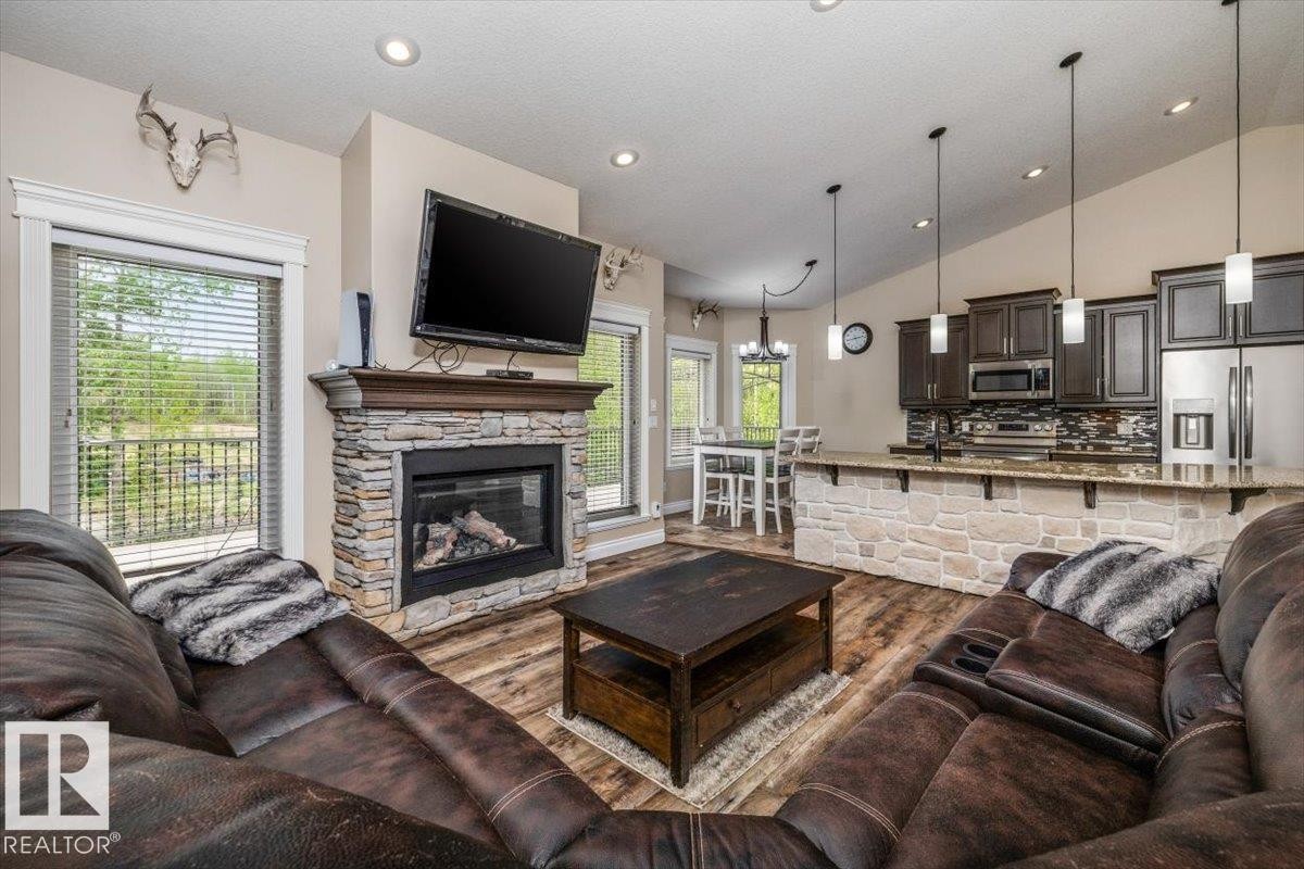 Open-concept living space with wood-finish flooring, a stone-faced fireplace, and recessed lighting - #6 2406 Twp Road 540, Rural Lac Ste. Anne County, AB - Indoor Photo Showing Living Room With Fireplace