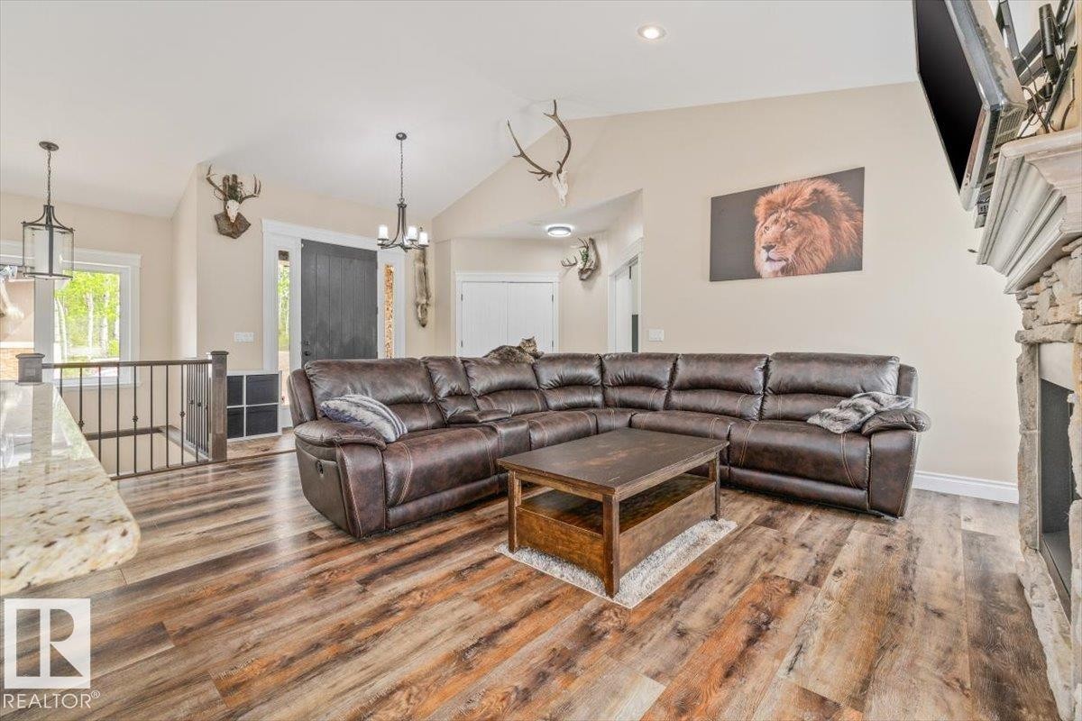 Spacious living area featuring vaulted ceilings, wood-finish flooring, and a stacked stone fireplace - #6 2406 Twp Road 540, Rural Lac Ste. Anne County, AB - Indoor Photo Showing Living Room