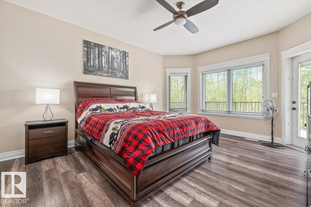 Spacious bedroom featuring wood-finish flooring, a ceiling fan, and multiple windows with white trim - #6 2406 Twp Road 540, Rural Lac Ste. Anne County, AB - Indoor Photo Showing Bedroom