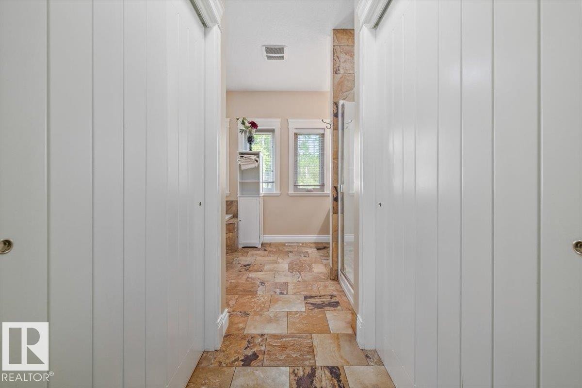 Hallway featuring board-and-batten style closet doors, varied-tone stone tile flooring, and a built-in shelving unit - #6 2406 Twp Road 540, Rural Lac Ste. Anne County, AB - Outdoor With Exterior