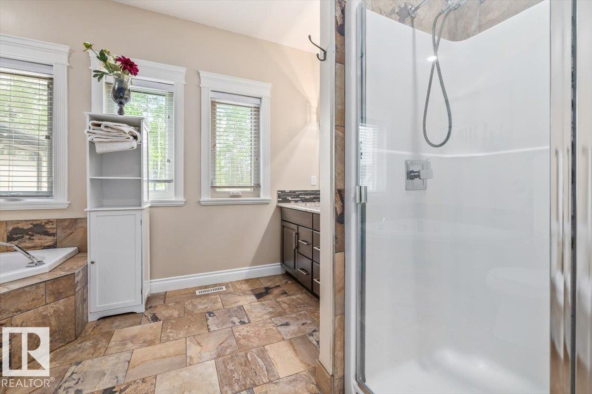 Walk-in shower with a glass enclosure, accompanied by a corner soaking tub with natural stone tile surround - #6 2406 Twp Road 540, Rural Lac Ste. Anne County, AB - Indoor Photo Showing Bathroom