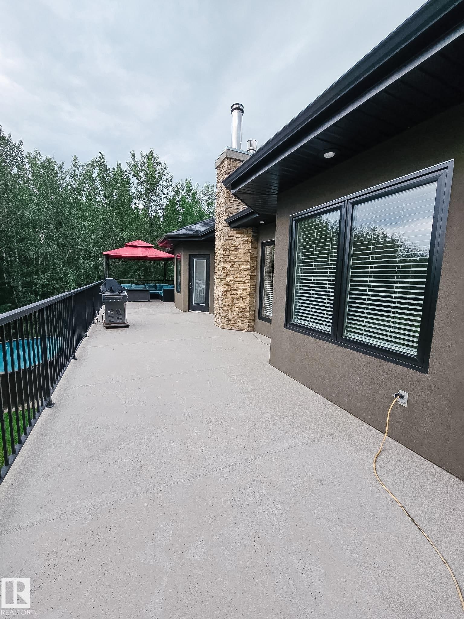 Expansive concrete patio with black metal railing - #6 2406 Twp Road 540, Rural Lac Ste. Anne County, AB - Outdoor With Exterior