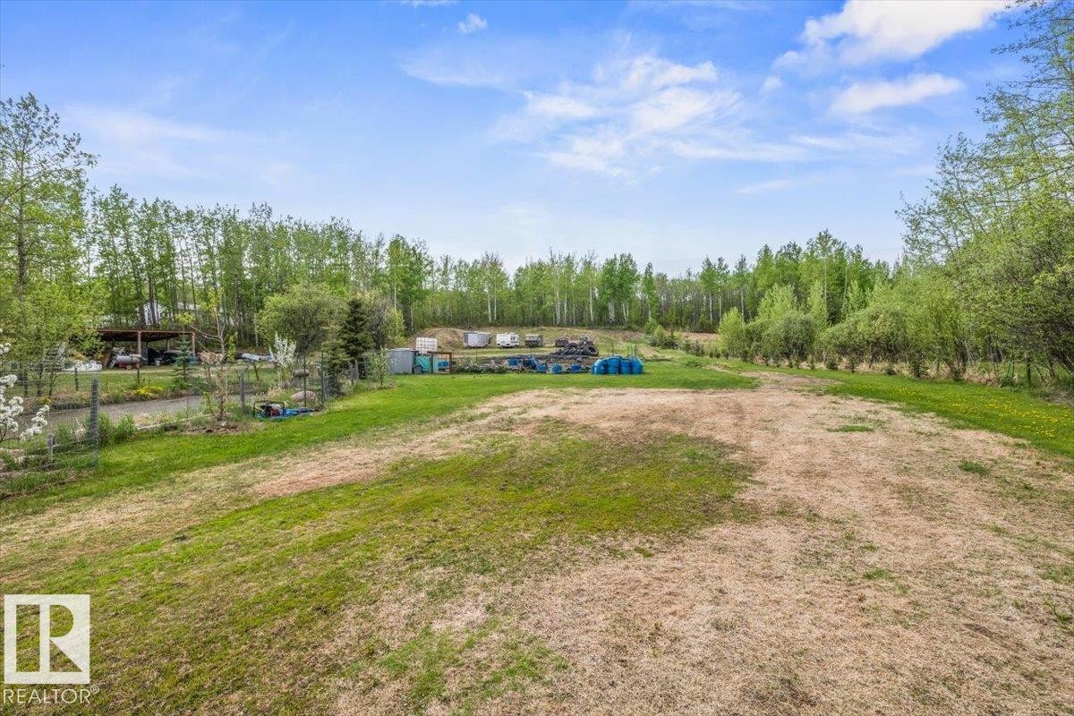 Expansive green space with distant tree lines, featuring a partial gravel driveway and a fenced area - #6 2406 Twp Road 540, Rural Lac Ste. Anne County, AB - Outdoor With View