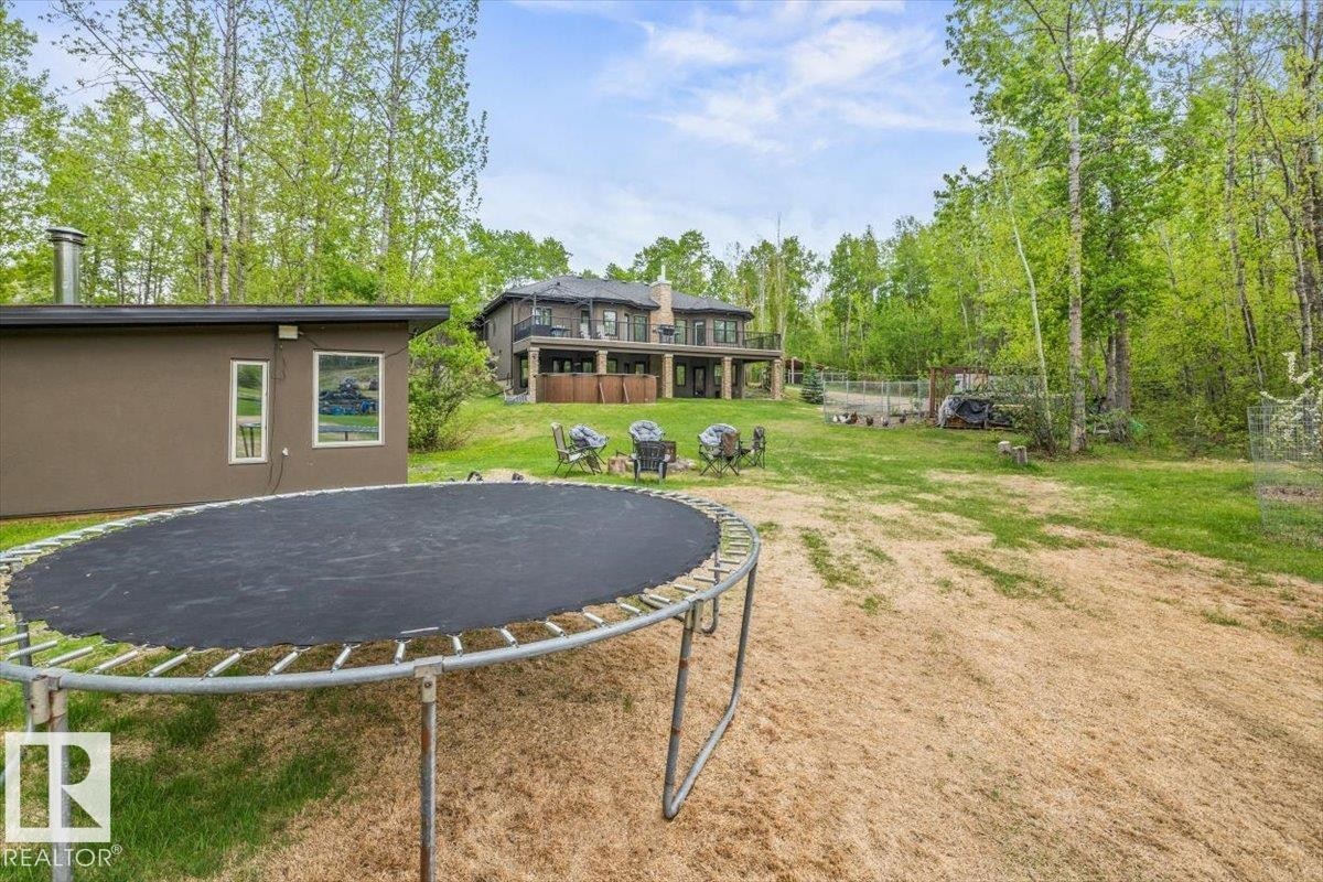Expansive outdoor area featuring a two-story residence with multiple balconies, a detached auxiliary structure, and a large grassy yard bordered by mature trees - #6 2406 Twp Road 540, Rural Lac Ste. Anne County, AB - Outdoor