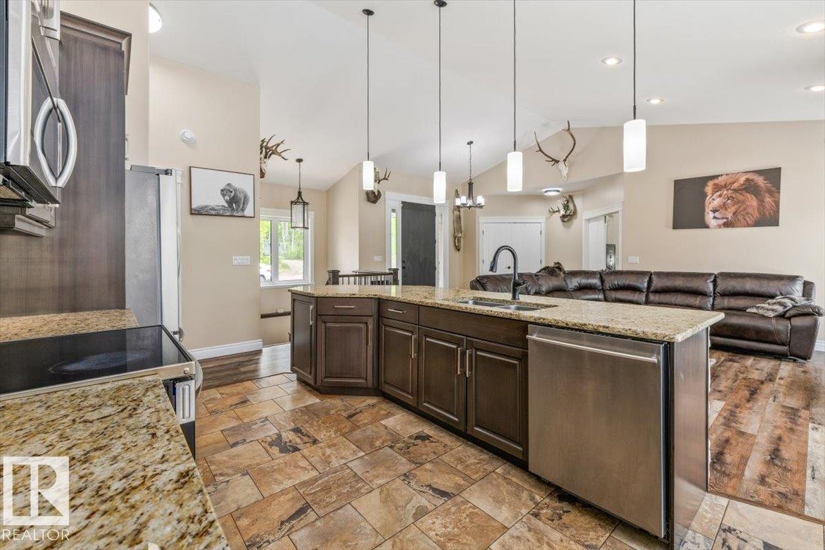 Open-concept kitchen featuring an expansive island with a built-in sink, granite countertops, and dark wood cabinetry - #6 2406 Twp Road 540, Rural Lac Ste. Anne County, AB - Indoor Photo Showing Kitchen With Upgraded Kitchen