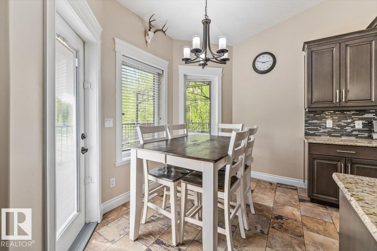 Spacious kitchen dining area featuring a vaulted ceiling with a chandelier, tile flooring, dark wood-finish cabinetry, and a multi-tone backsplash - #6 2406 Twp Road 540, Rural Lac Ste. Anne County, AB - Indoor Photo Showing Dining Room