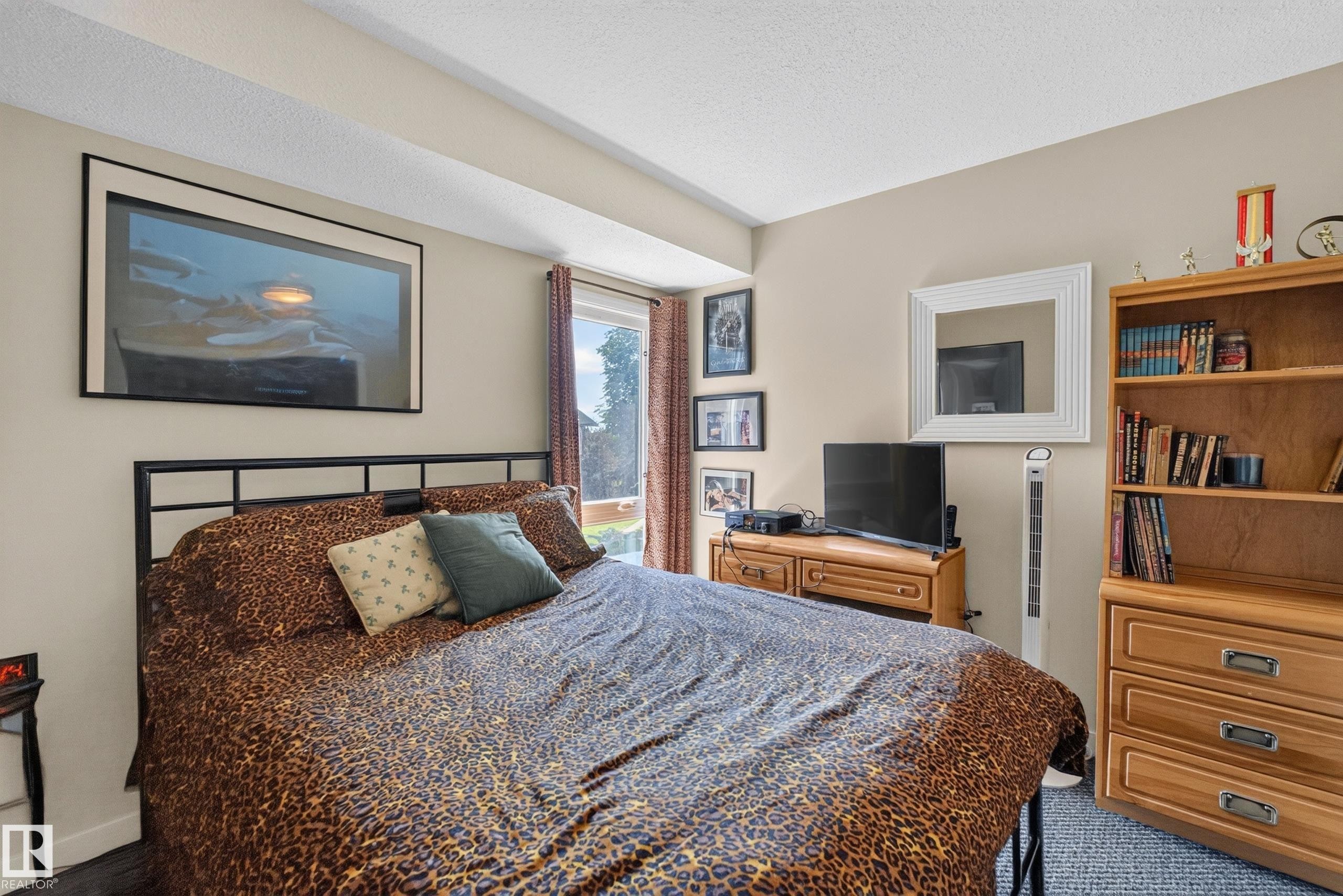 Bedroom featuring a black metal bed frame, light-colored walls, and textured carpet flooring - 12062 157 Avenue, Edmonton, AB