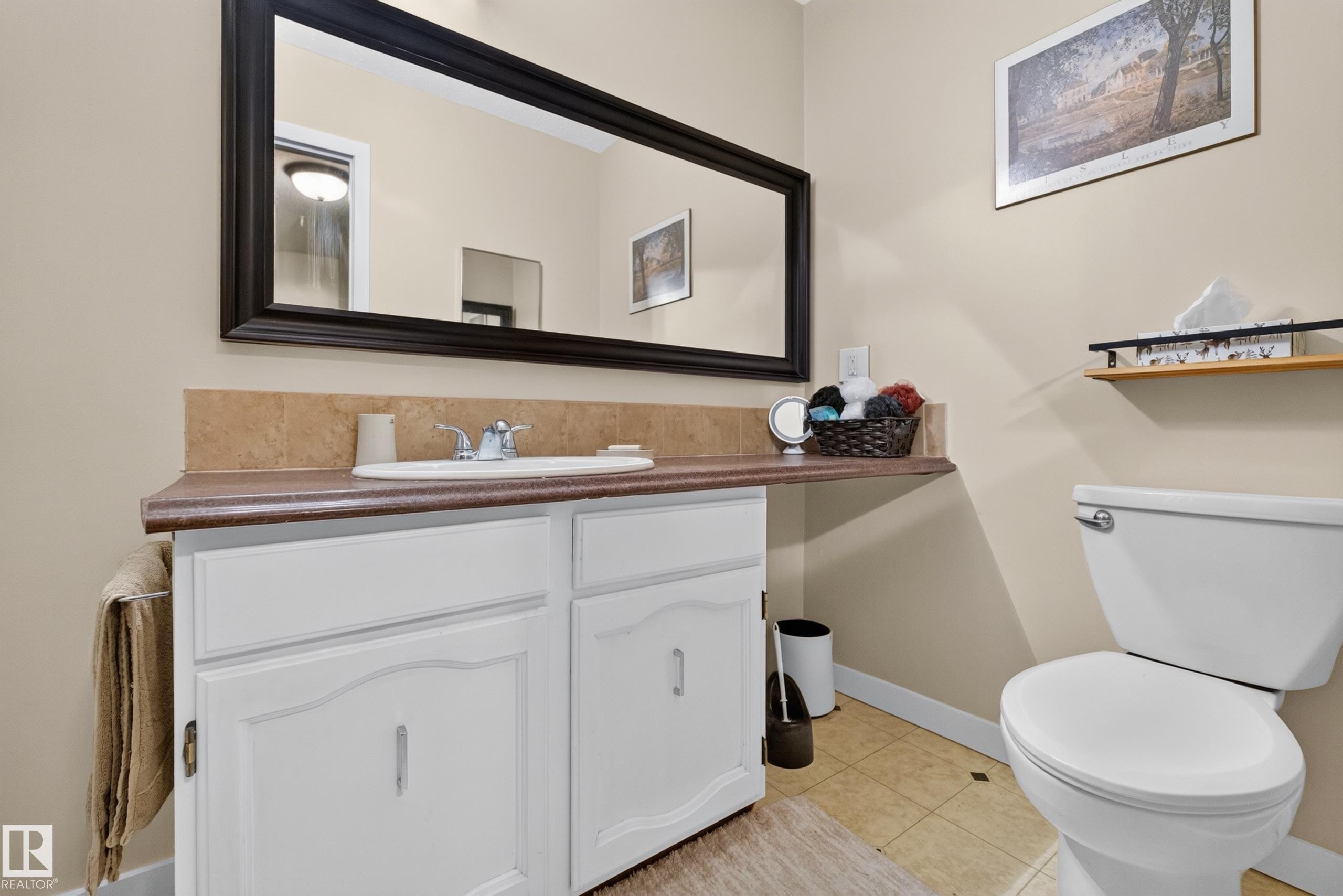 Bathroom featuring a white vanity with a laminate countertop, integrated sink, and chrome faucet - 12062 157 Avenue, Edmonton, AB