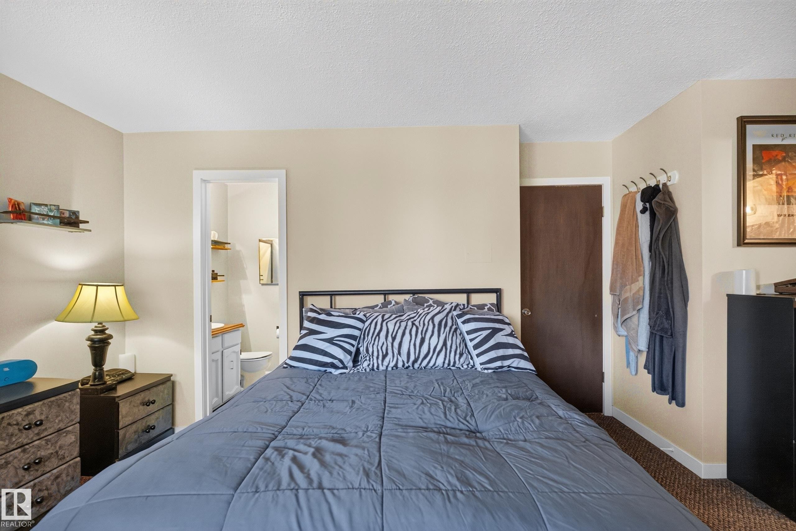 Bedroom featuring a metal bed frame, light beige walls, and brown carpet flooring - 12062 157 Avenue, Edmonton, AB