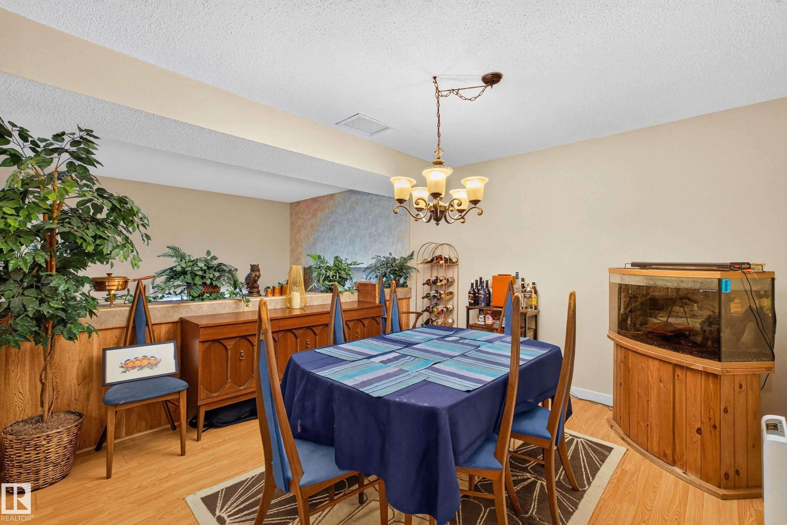 Dining area featuring wood-finish flooring, a brass-toned chandelier with frosted glass shades, and light-toned wall paint - 12062 157 Avenue, Edmonton, AB