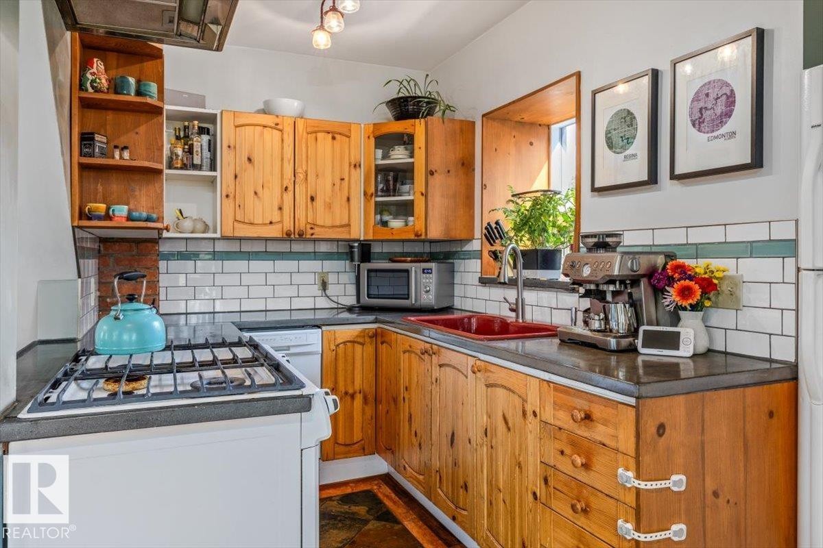 Kitchen featuring wood-finish cabinetry, white subway tile backsplash with accent border, and dark countertops - 11603 70 Street Nw, Edmonton, AB