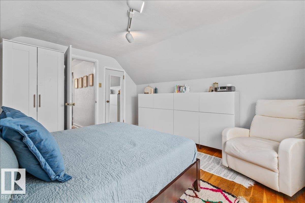 Bedroom featuring sloped ceilings, track lighting, and wood-finish flooring - 11603 70 Street Nw, Edmonton, AB