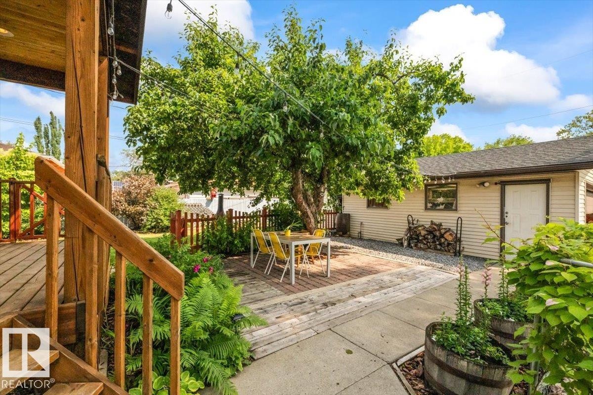 Outdoor living area featuring a wood deck, a brick patio, and a mature shade tree - 11603 70 Street Nw, Edmonton, AB