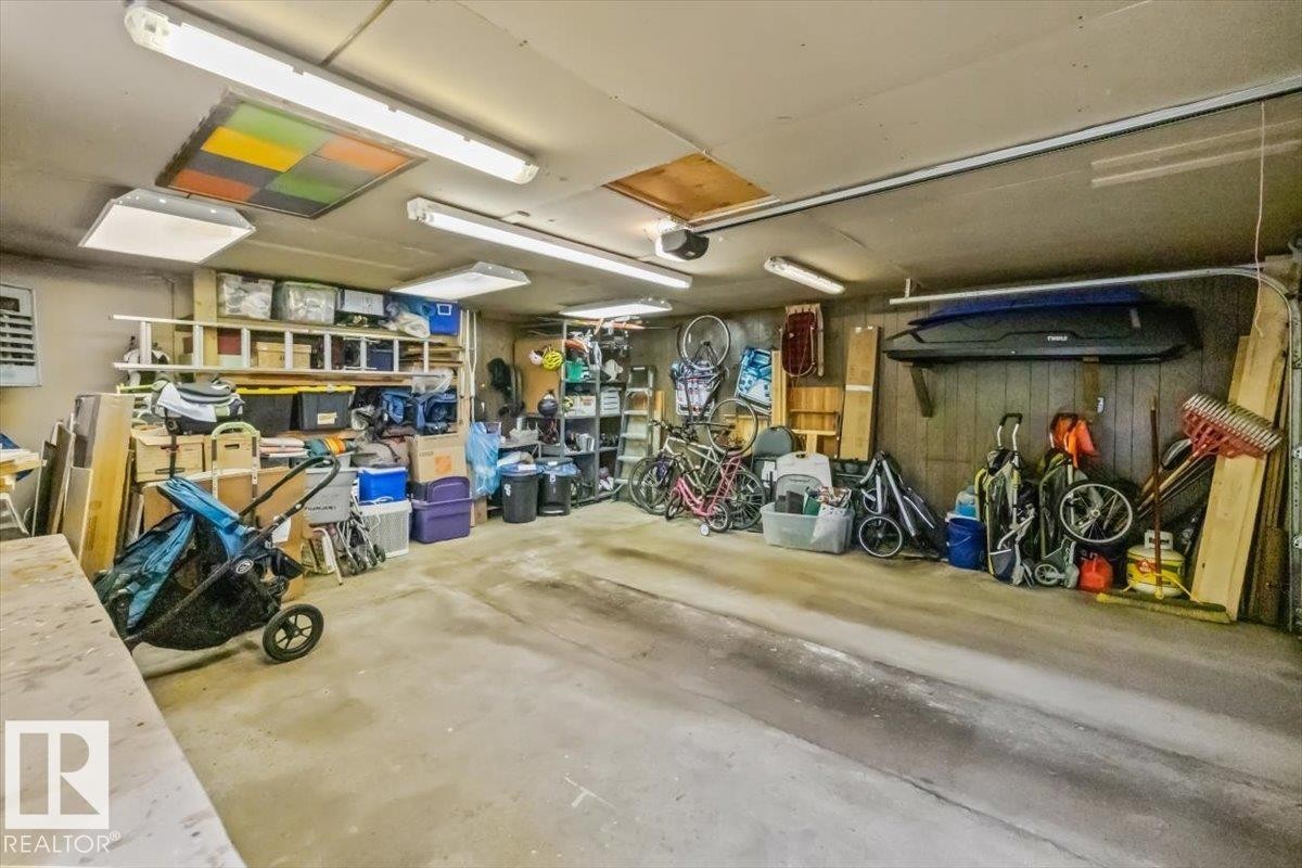 Attached garage featuring concrete flooring, overhead fluorescent lighting, and built-in shelving - 11603 70 Street Nw, Edmonton, AB