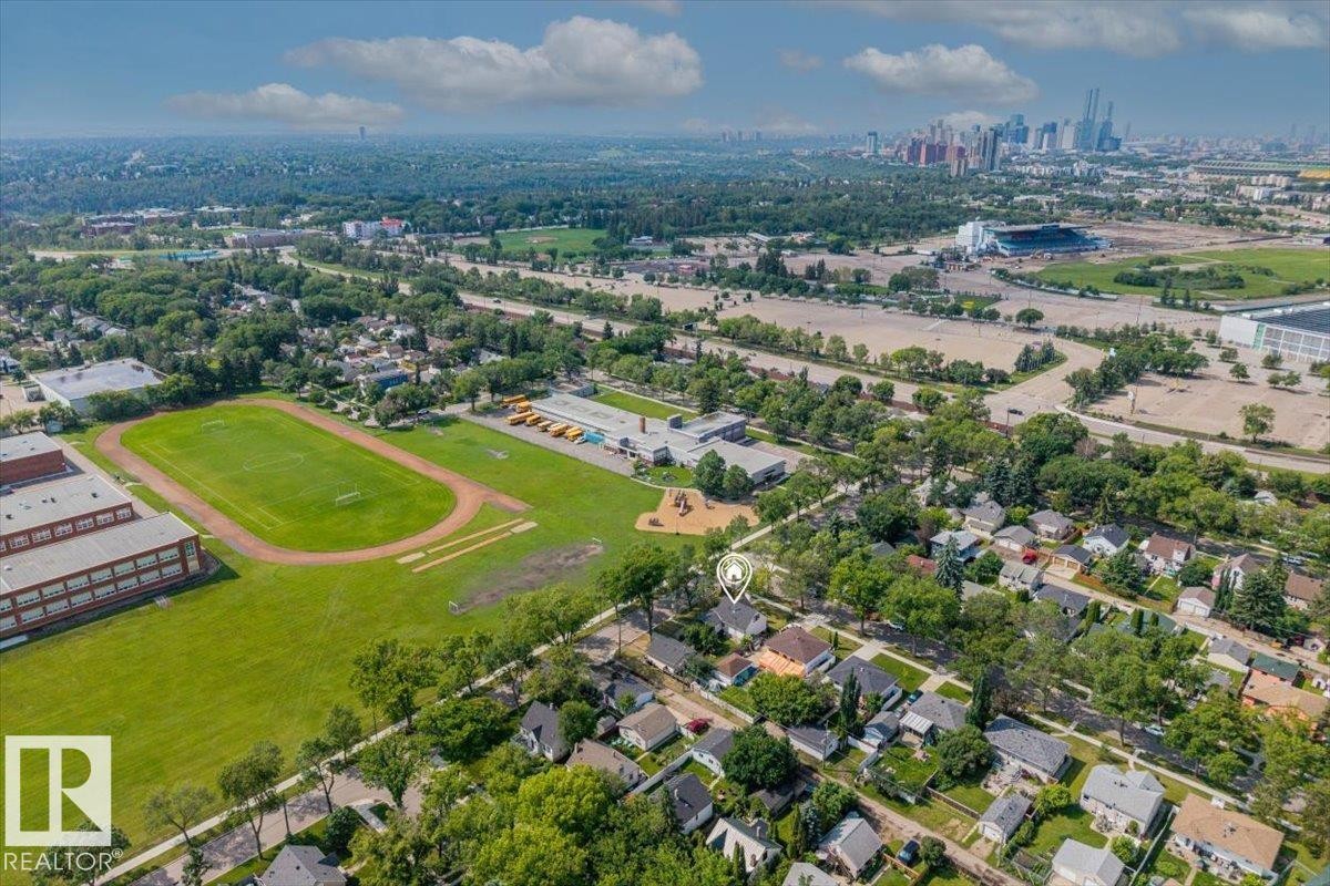 Aerial view of a residential neighborhood with established trees, featuring a school building with a track and sports field - 11603 70 Street Nw, Edmonton, AB