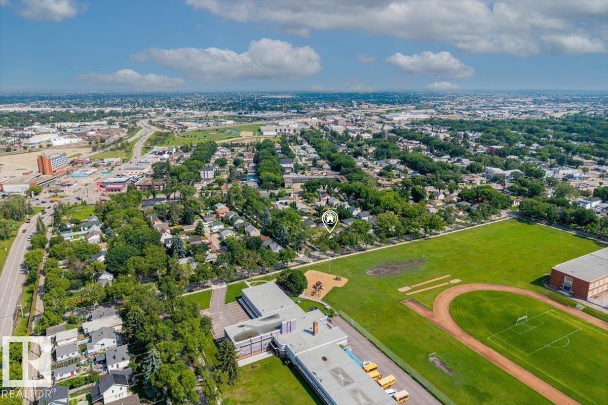 Aerial perspective showcasing a residential area with extensive tree canopies, bordered by a large athletic field and a multi-story building - 11603 70 Street Nw, Edmonton, AB