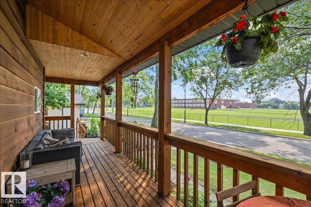Covered front porch featuring natural wood siding and decking - 11603 70 Street Nw, Edmonton, AB