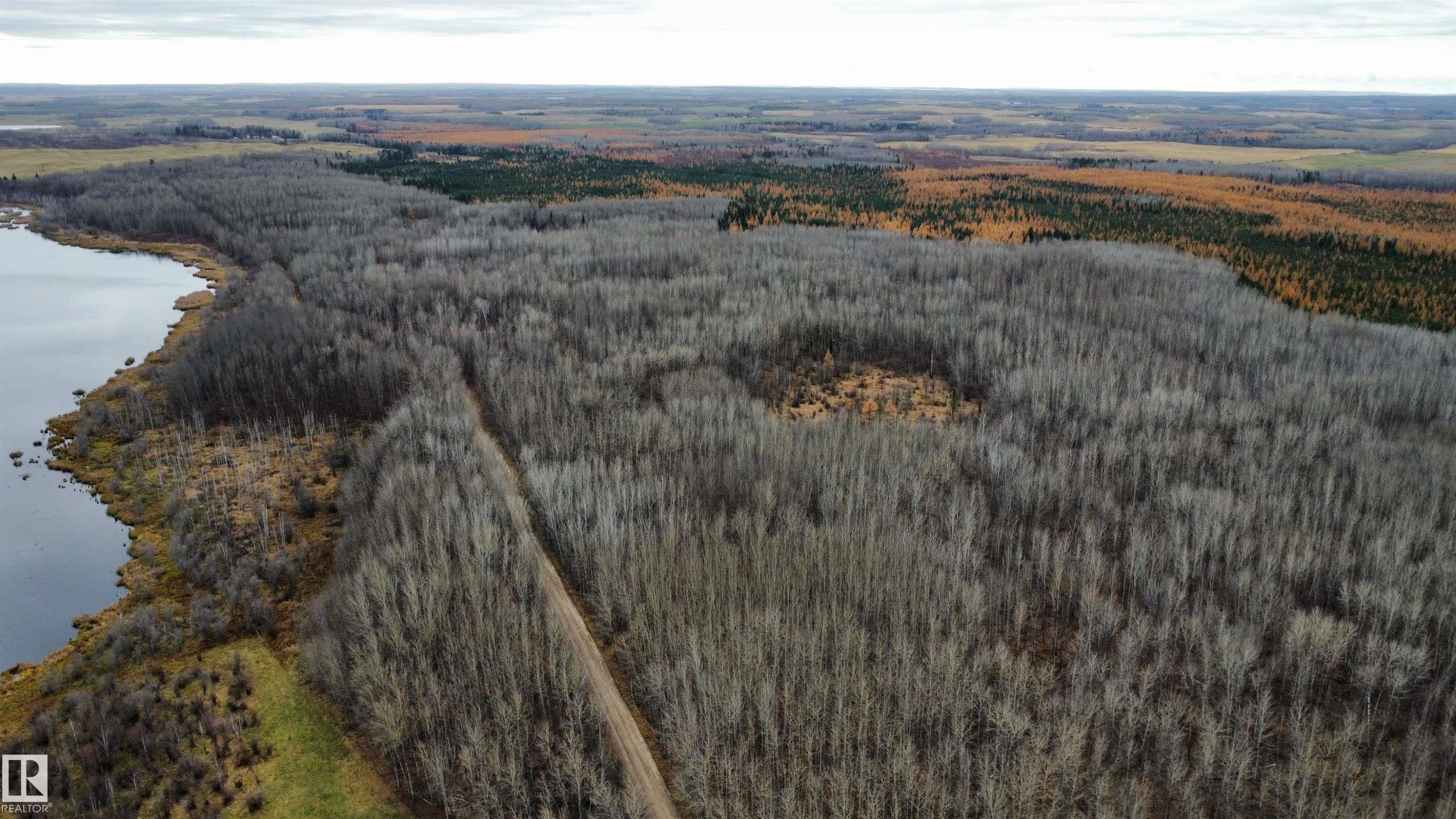 Expansive land parcel featuring a significant body of water, extensive tree coverage, varied foliage, and a defined ground path - Rge Rd 62, Rural Barrhead County, AB