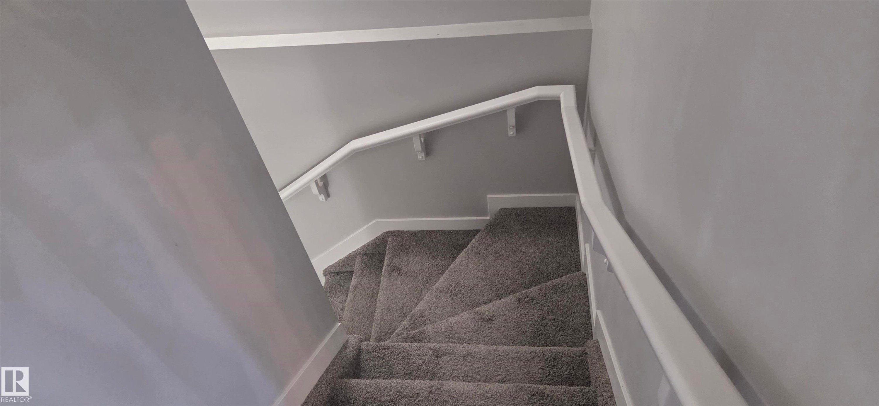 Carpeted staircase with white trim, white handrail, and light gray wall paint - 16505 133 Street, Edmonton, AB