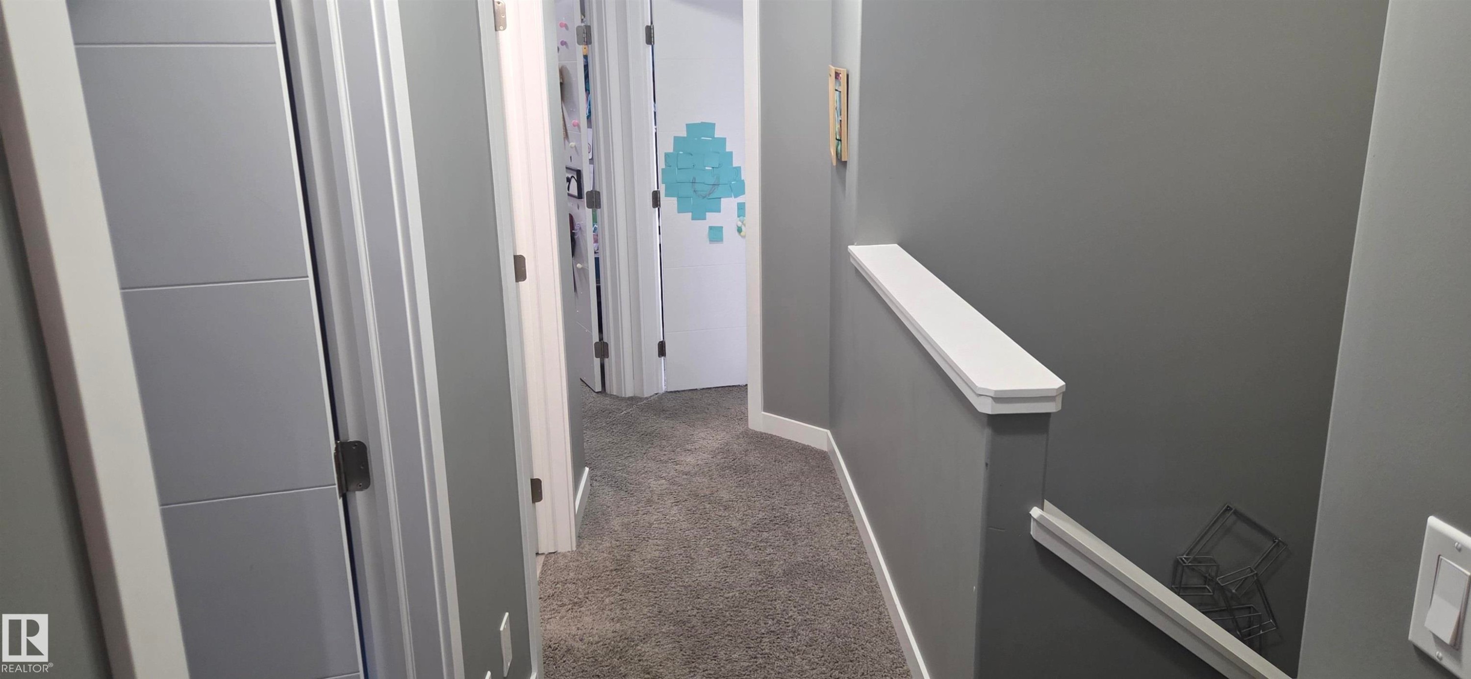 Hallway featuring gray wall paint, white trim, and gray carpeted flooring - 16505 133 Street, Edmonton, AB