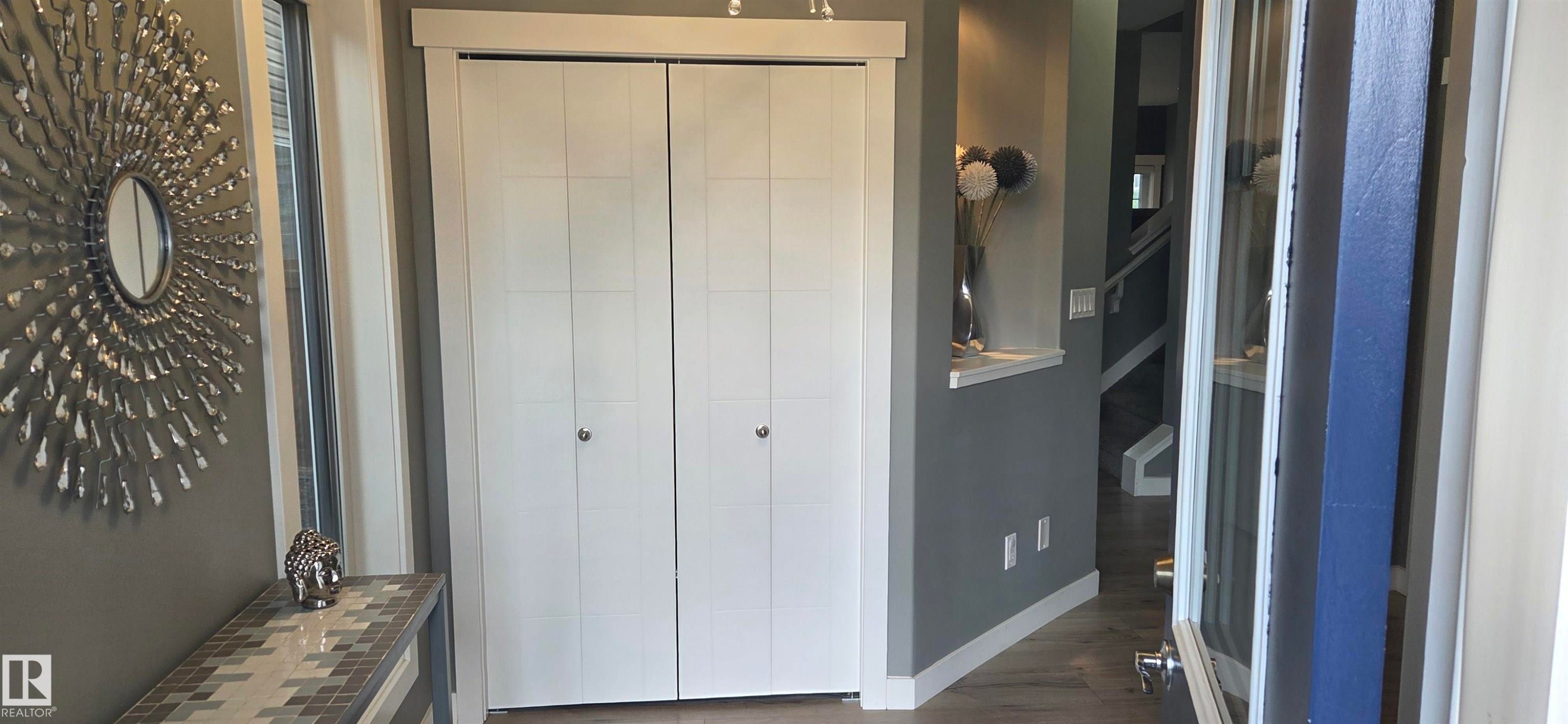 Entryway featuring a bi-fold closet, recessed wall niche, and wood-finish flooring - 16505 133 Street, Edmonton, AB
