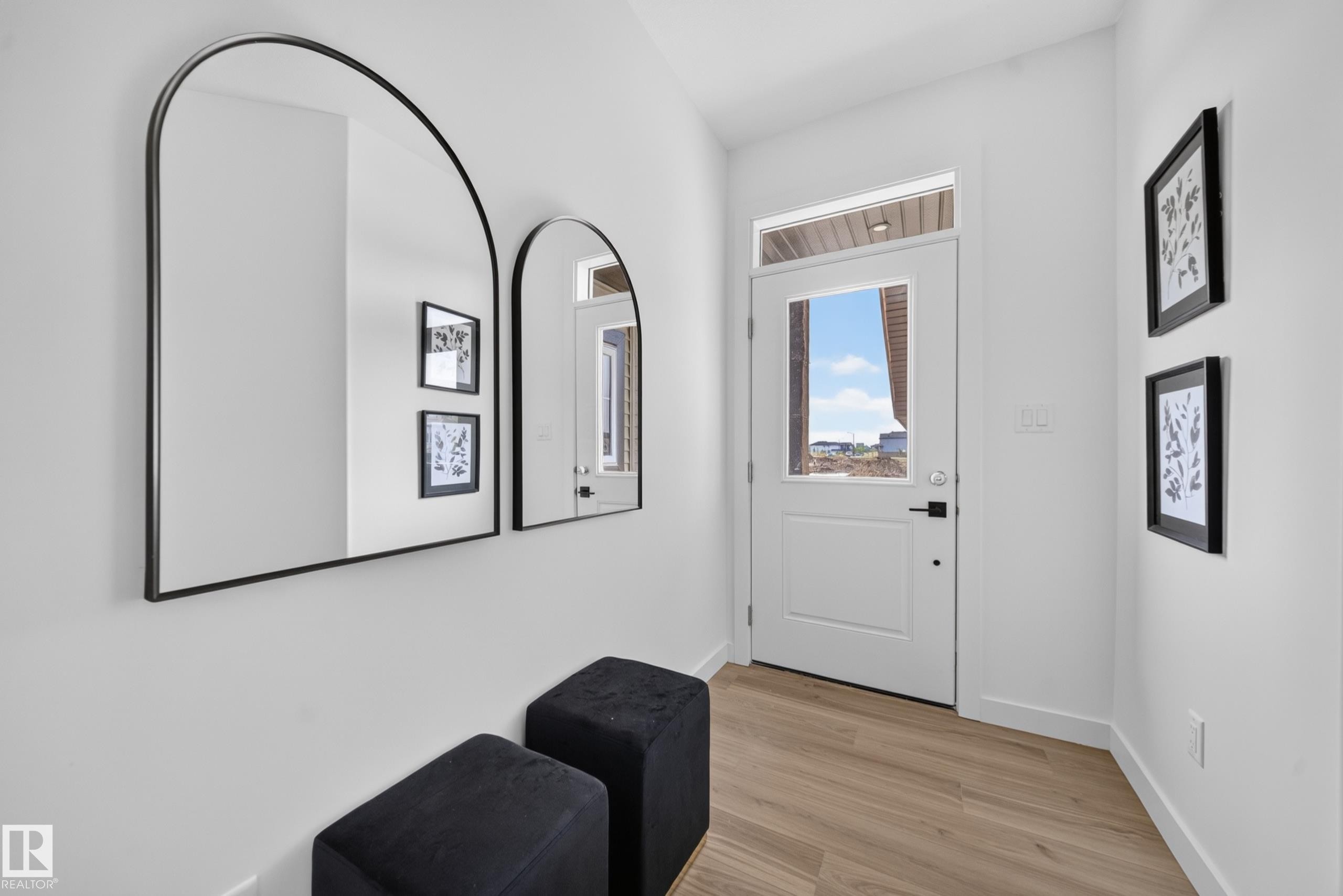 Entryway featuring wood-finish flooring, white walls, and a door with a clear glass insert and transom window - 523 Ashgrove Circle, Leduc, AB