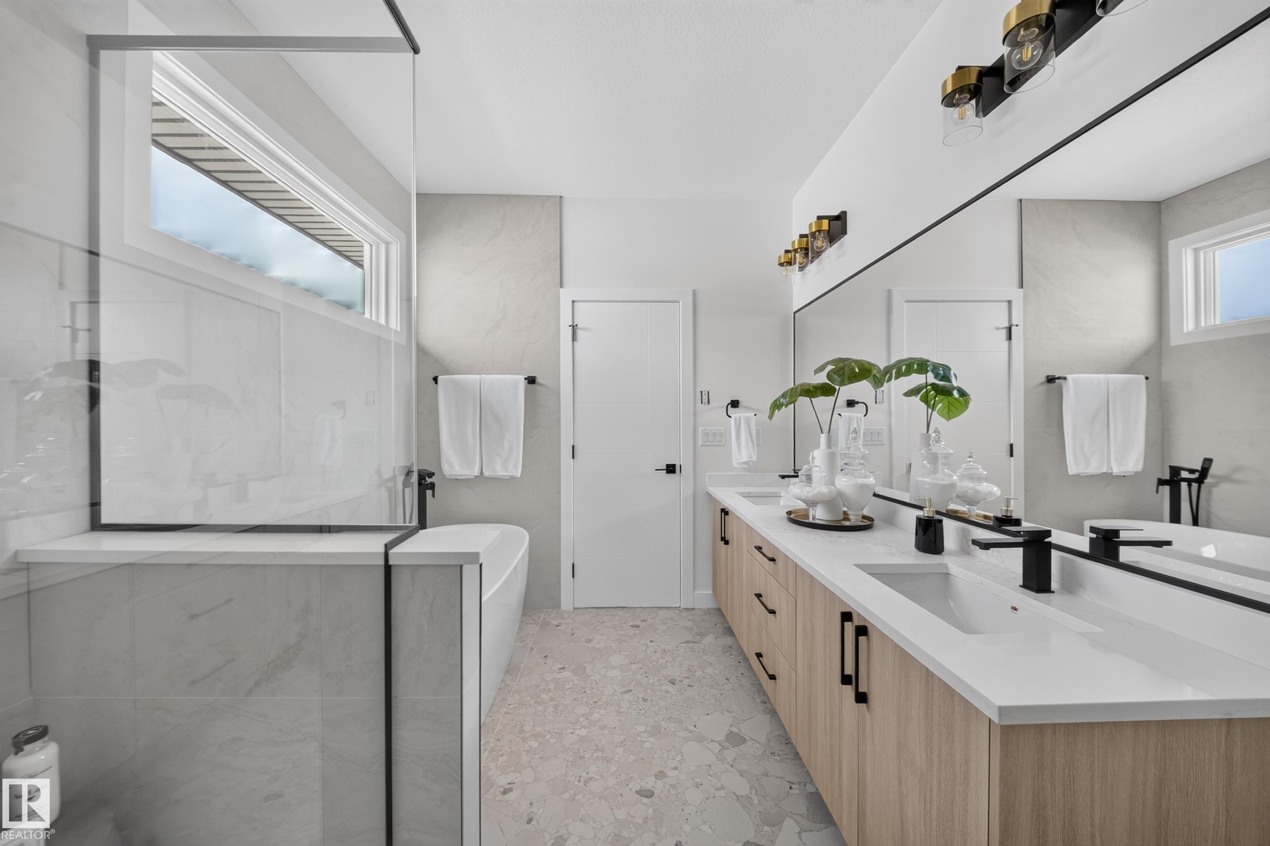 Modern bathroom featuring a dual vanity with light wood-finish cabinetry, white countertops, and black fixtures - 523 Ashgrove Circle, Leduc, AB