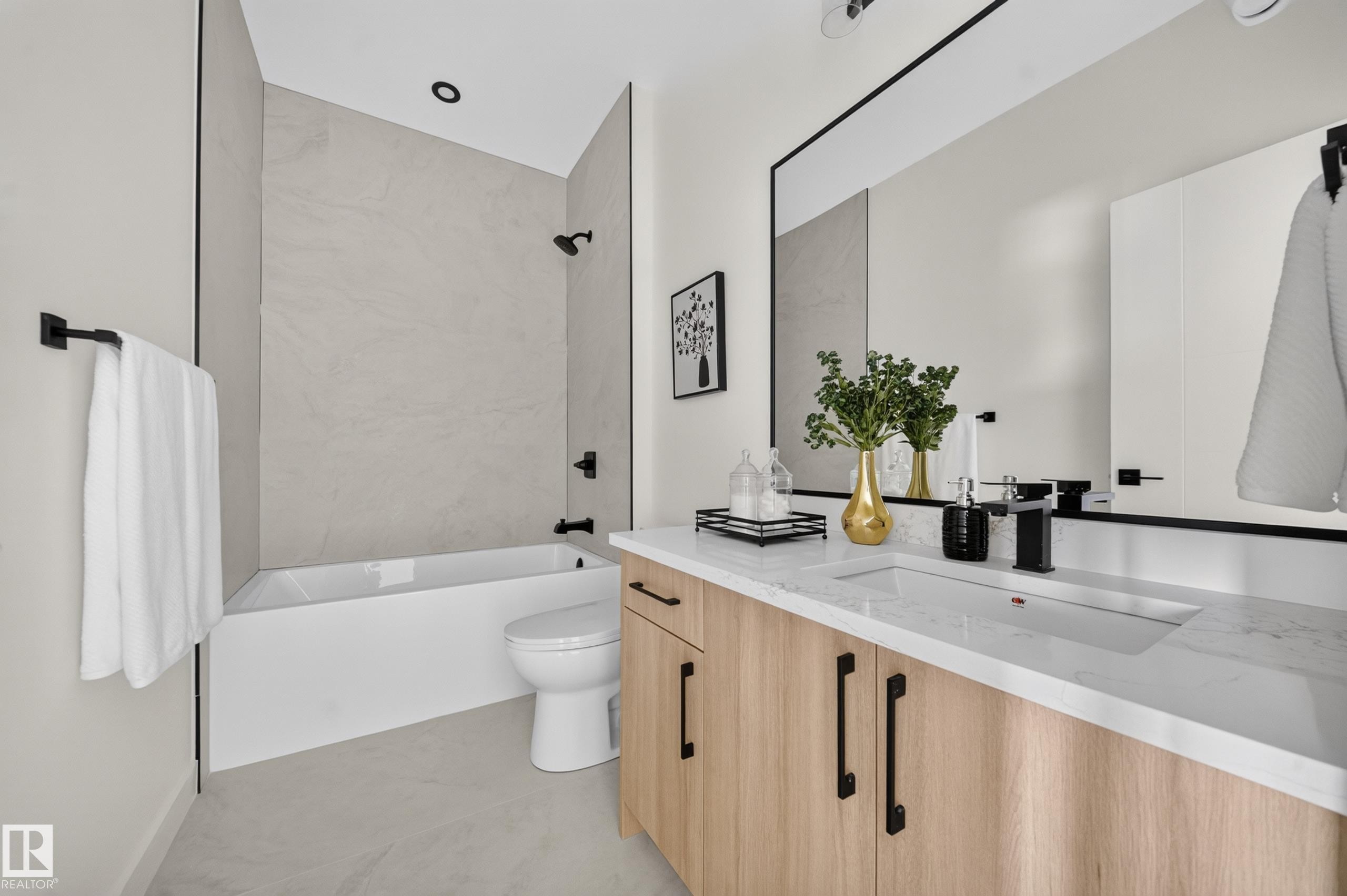 Contemporary bathroom featuring a light wood-finish vanity with black hardware, an integrated sink, and a white countertop - 523 Ashgrove Circle, Leduc, AB