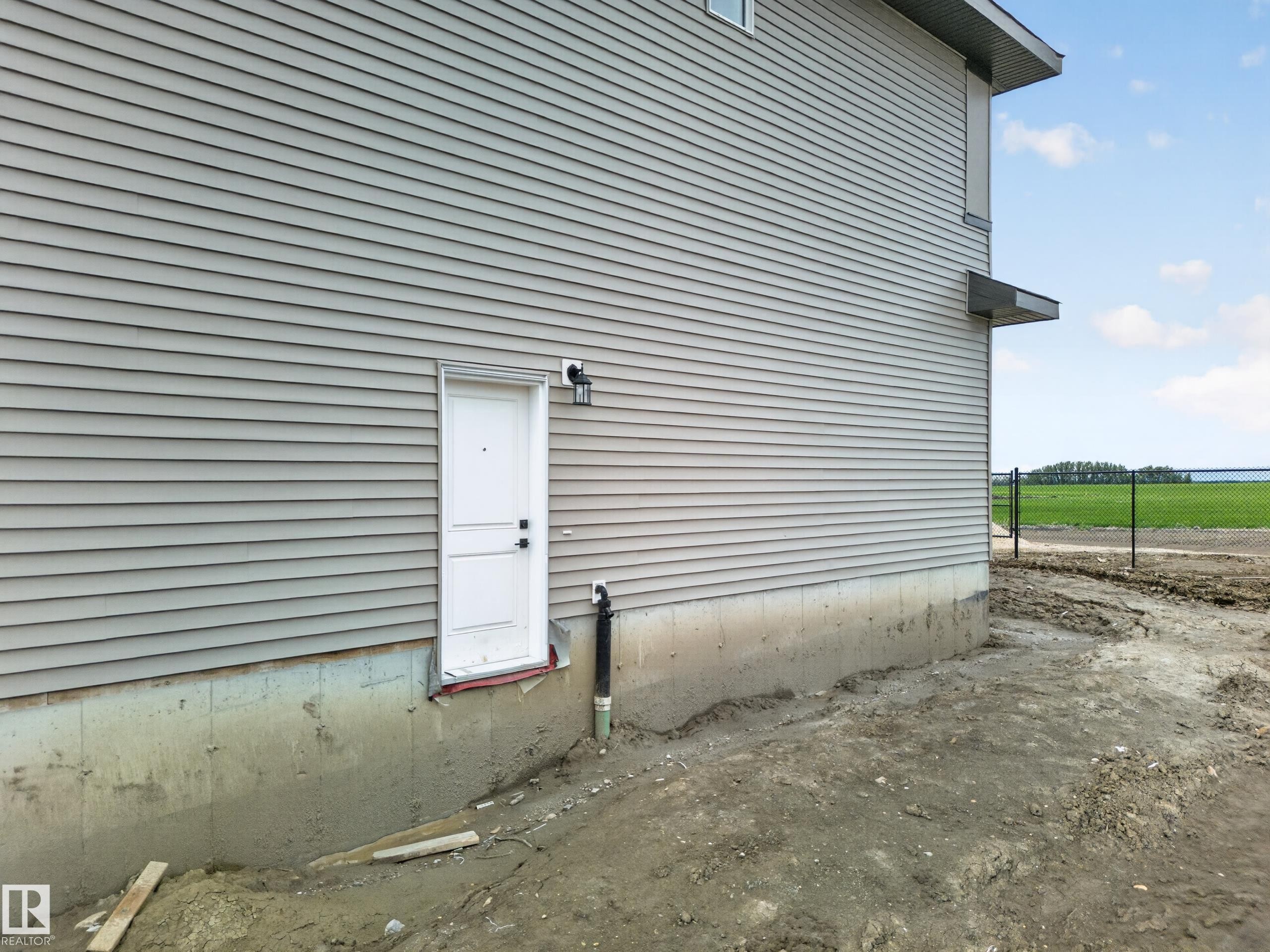 Neutral-toned siding exterior with a white entry door and black exterior sconce - 523 Ashgrove Circle, Leduc, AB