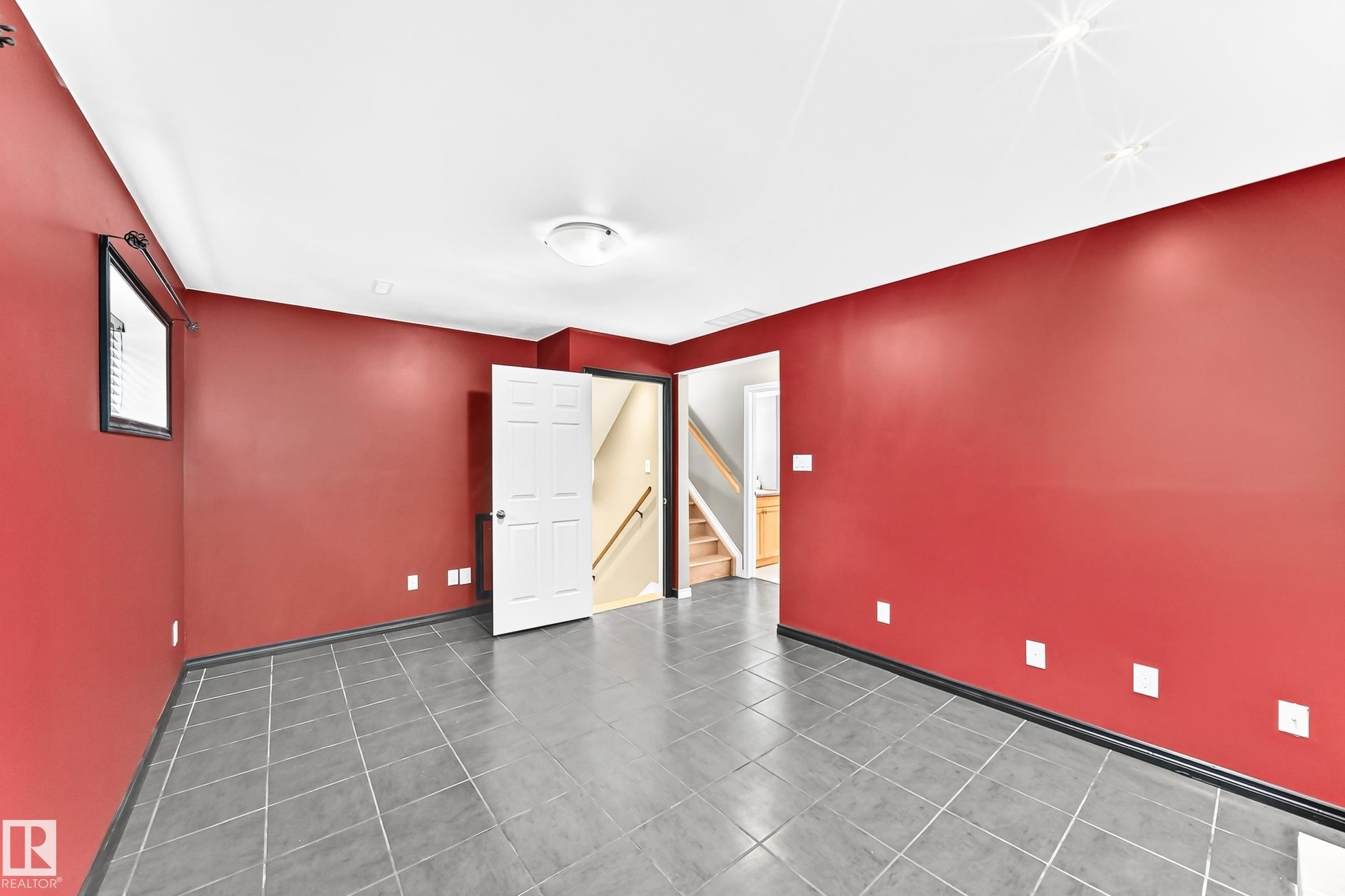 Spacious room featuring neutral tile flooring, vibrant red walls, and bright white trim - 1763 48A Street, Edmonton, AB