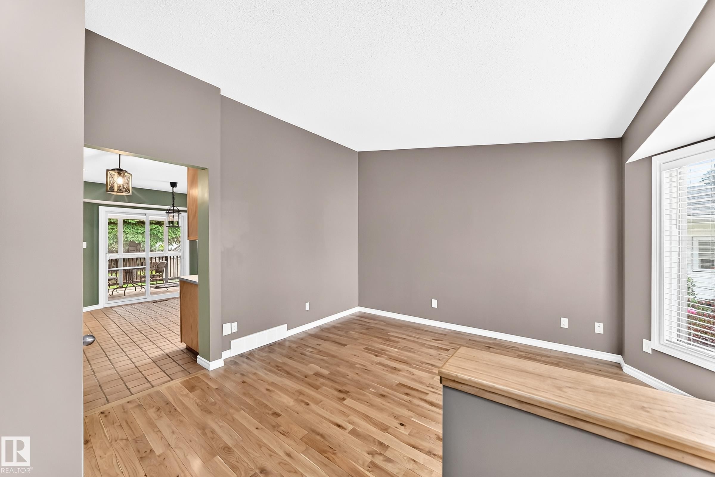 Spacious living area featuring wood-finish flooring, neutral wall tones, and a bay window - 1763 48A Street, Edmonton, AB