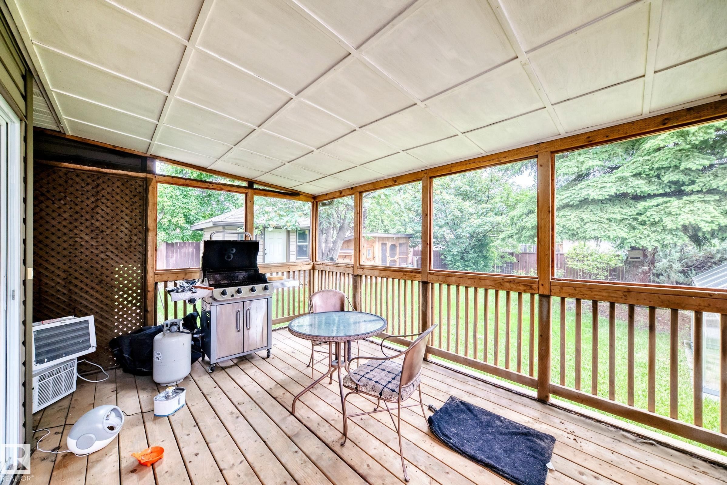Expansive screened porch featuring wood-finish decking, a white panel ceiling, and wood-framed screen panels - 1763 48A Street, Edmonton, AB