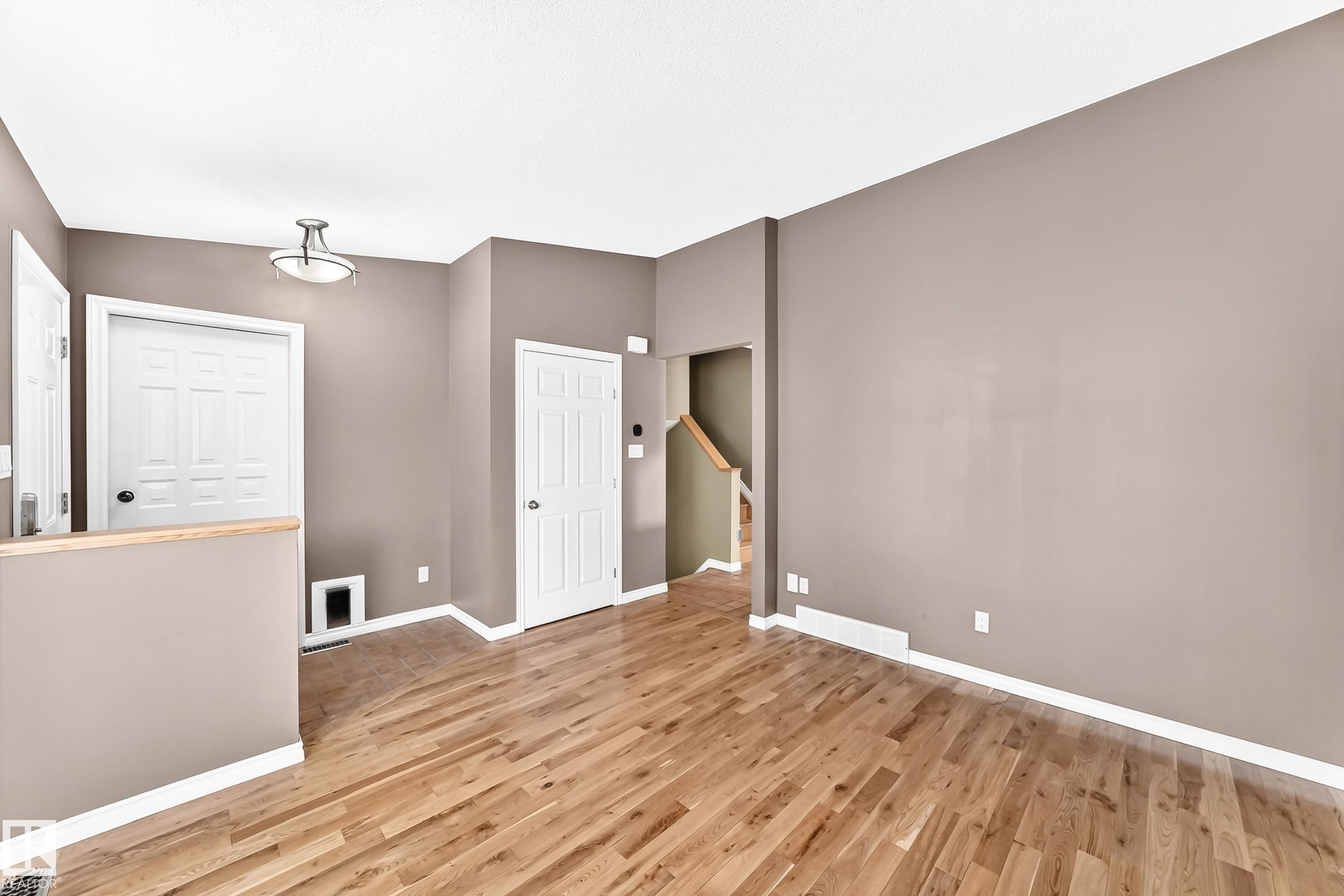 Hardwood flooring throughout a spacious room with light brown walls and white trim - 1763 48A Street, Edmonton, AB