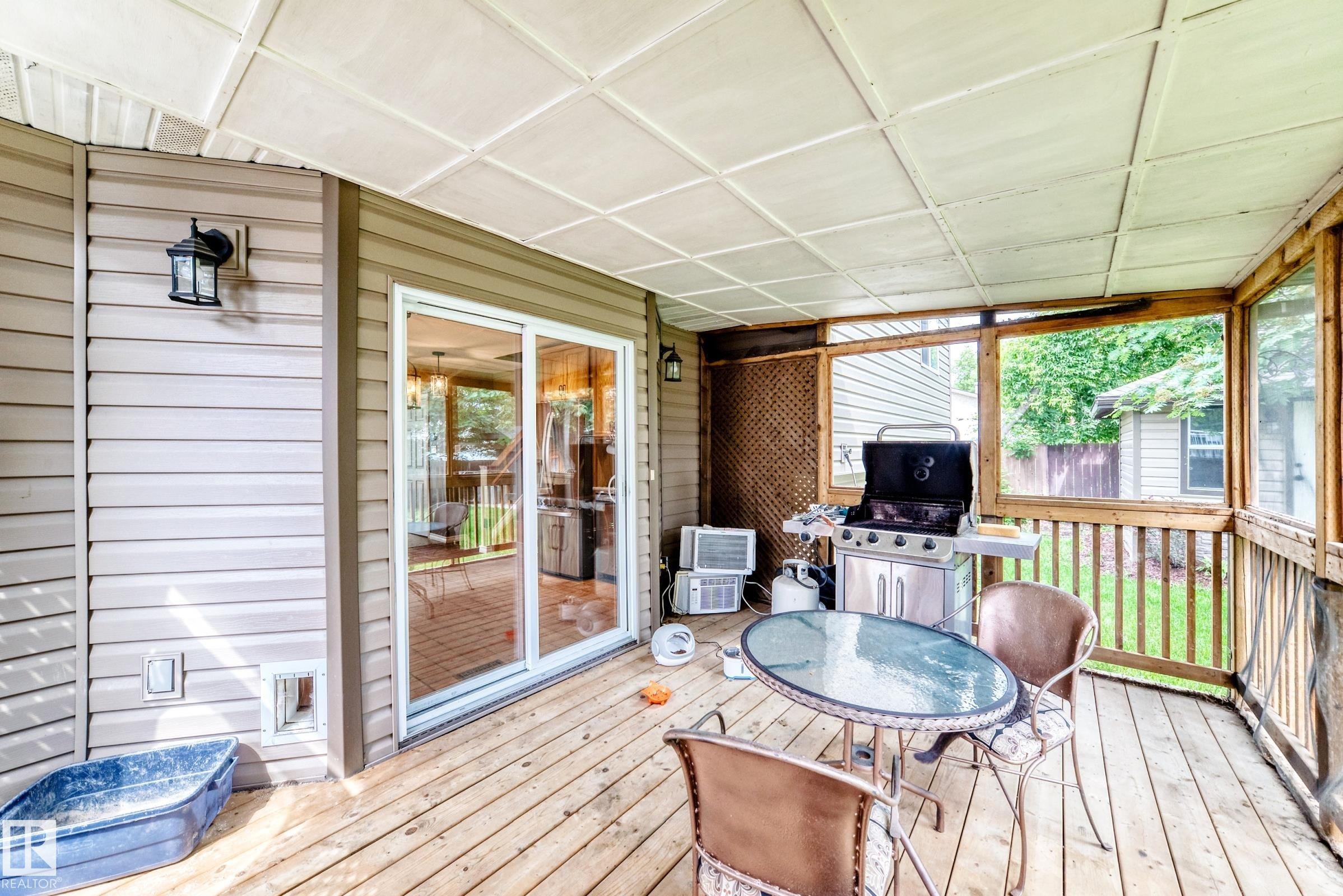 Screened-in porch featuring wood-finish flooring, a paneled ceiling, and a sliding glass door - 1763 48A Street, Edmonton, AB