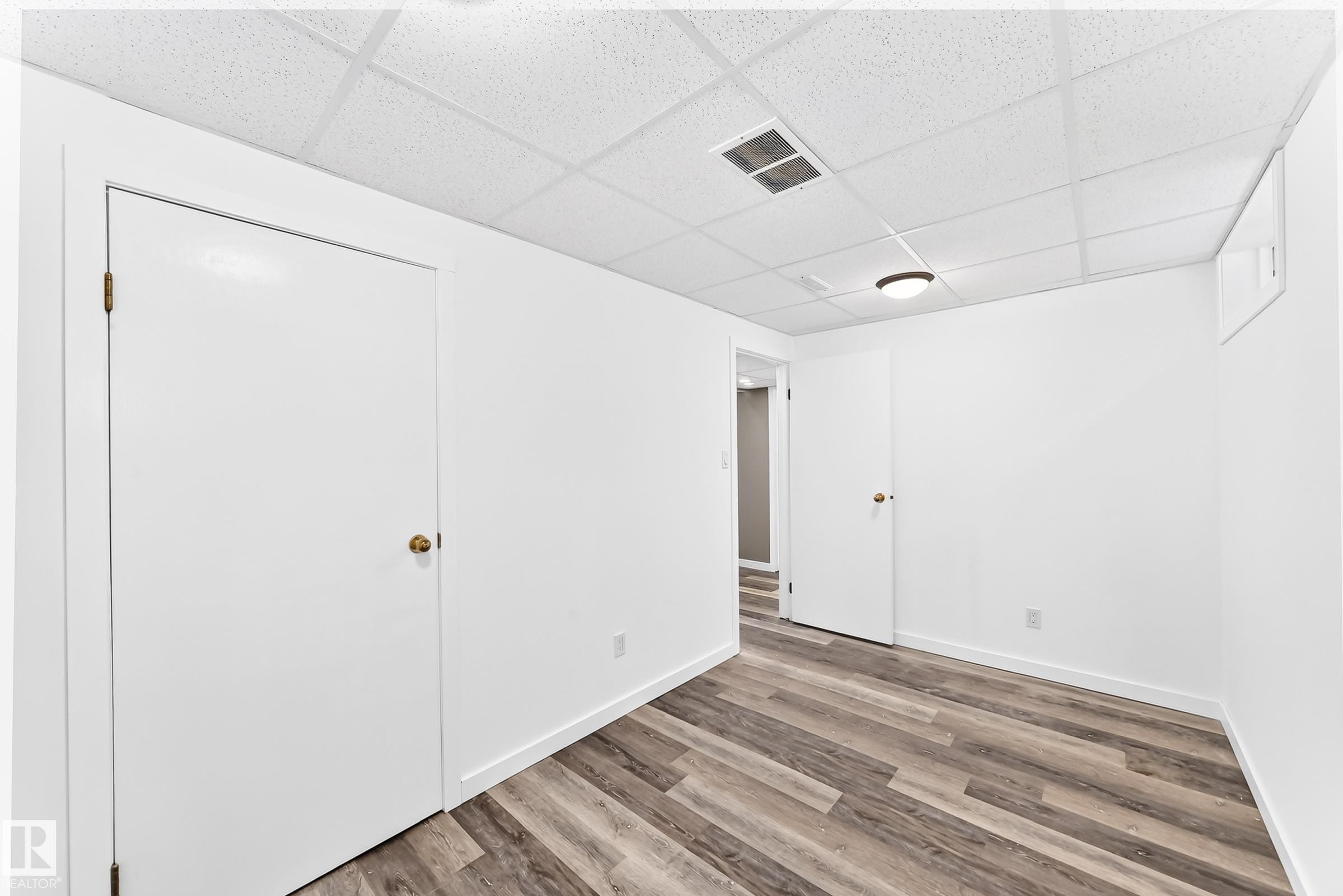 Room featuring wood-finish flooring, white walls, and a drop ceiling with recessed lighting - 1763 48A Street, Edmonton, AB