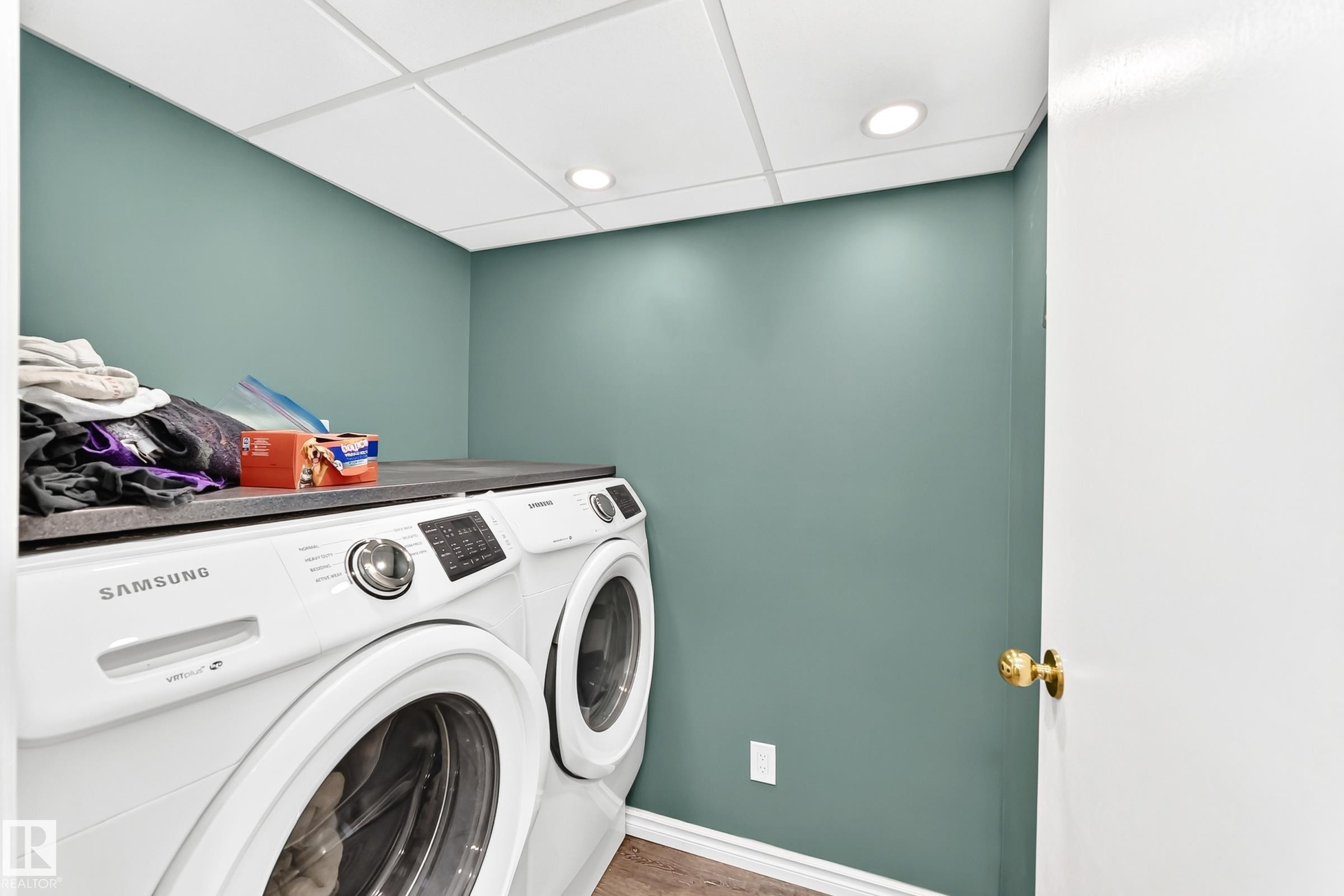 Dedicated laundry area featuring a countertop surface above side-by-side appliances, recessed ceiling lighting, and wood-finish flooring - 1763 48A Street, Edmonton, AB