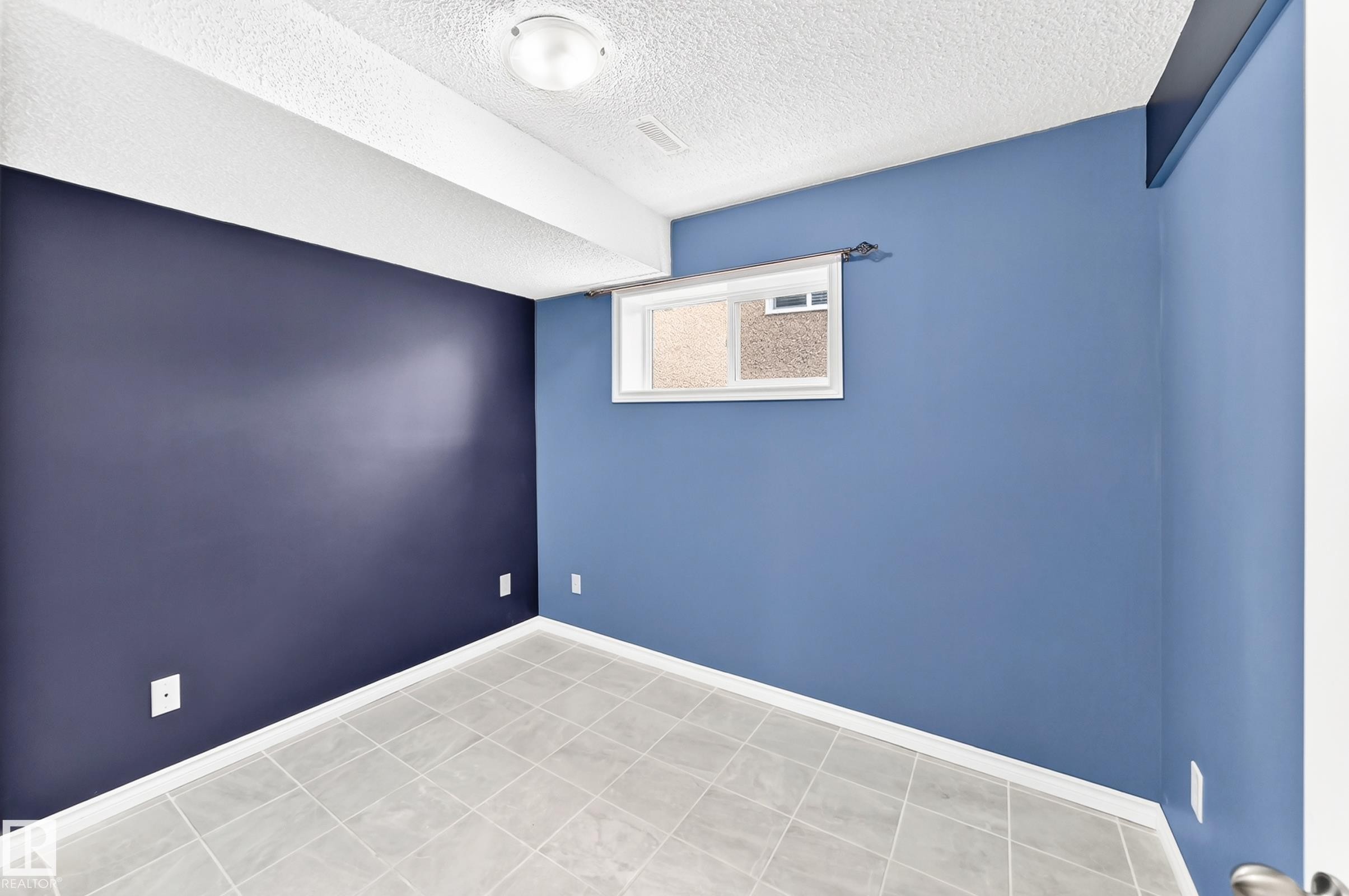 Room featuring light gray square floor tiles and contrasting blue wall tones - 1763 48A Street, Edmonton, AB