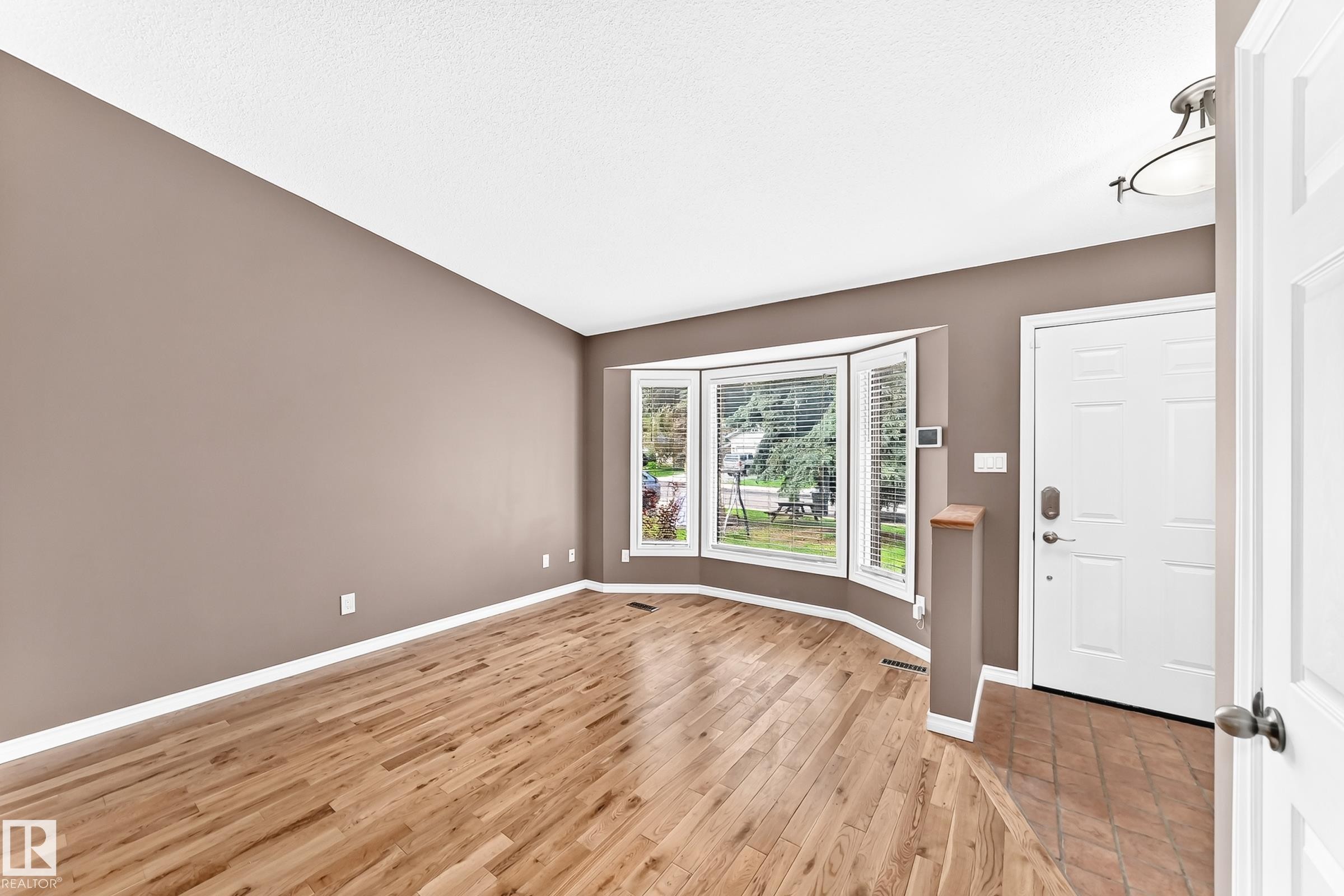 Living space featuring wood-finish flooring, a bay window with blinds, and neutral wall tones - 1763 48A Street, Edmonton, AB