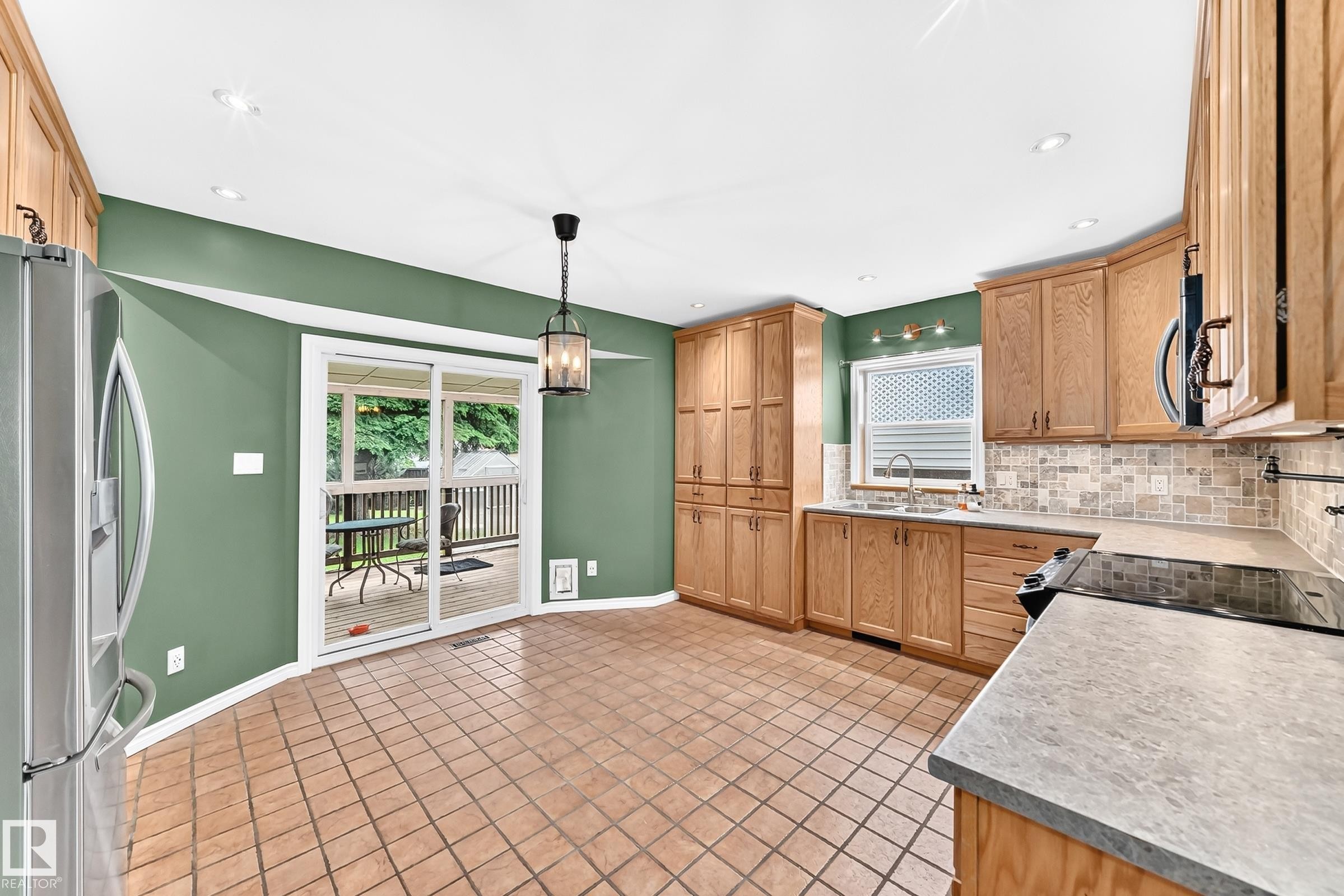 Kitchen featuring light wood cabinetry, stone-finish countertops, and a tiled backsplash - 1763 48A Street, Edmonton, AB
