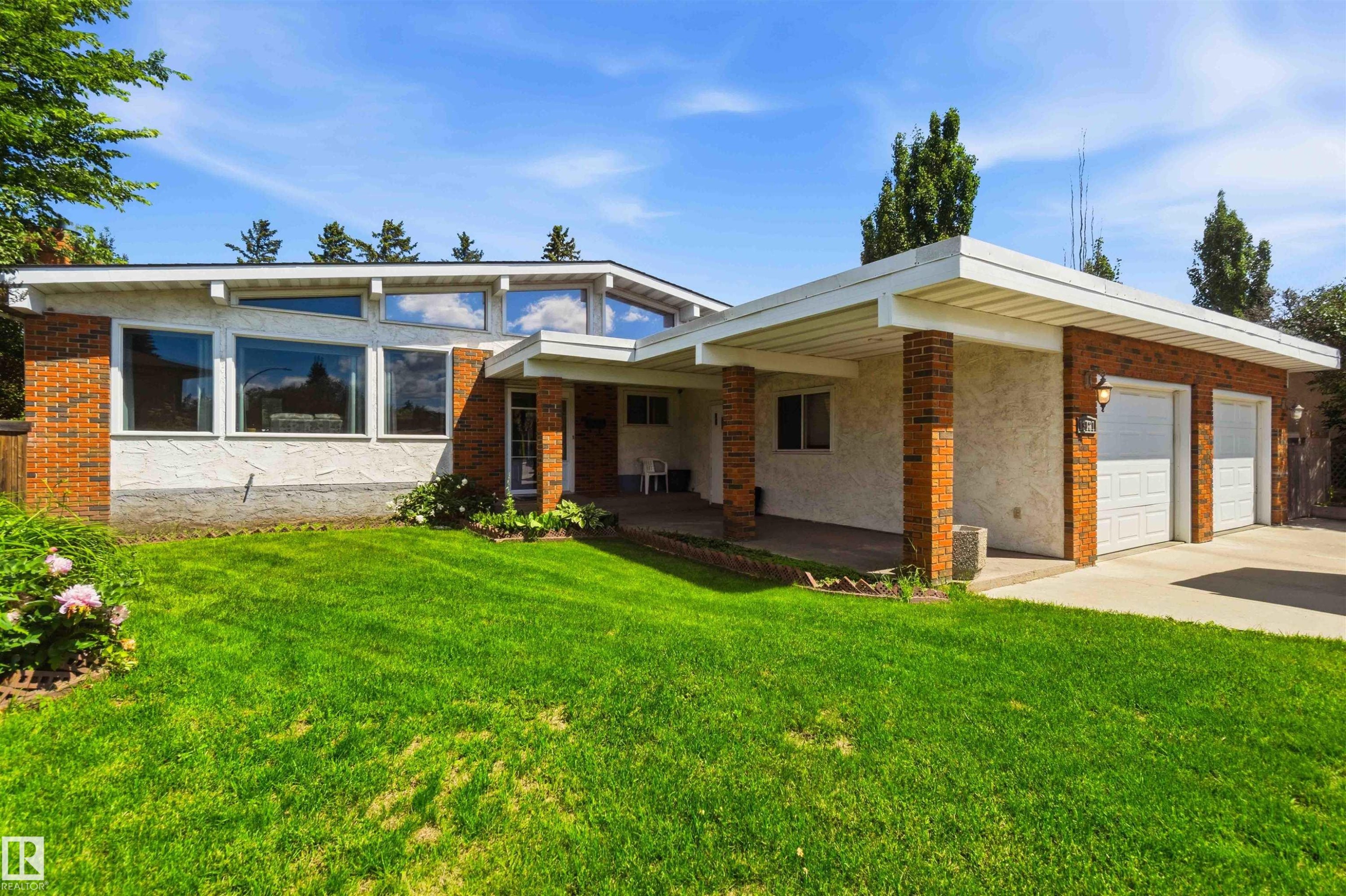Ranch-style exterior with a low-pitch roofline, brick and stucco facade, and an attached two-car garage - 13121 122 Street, Edmonton, AB