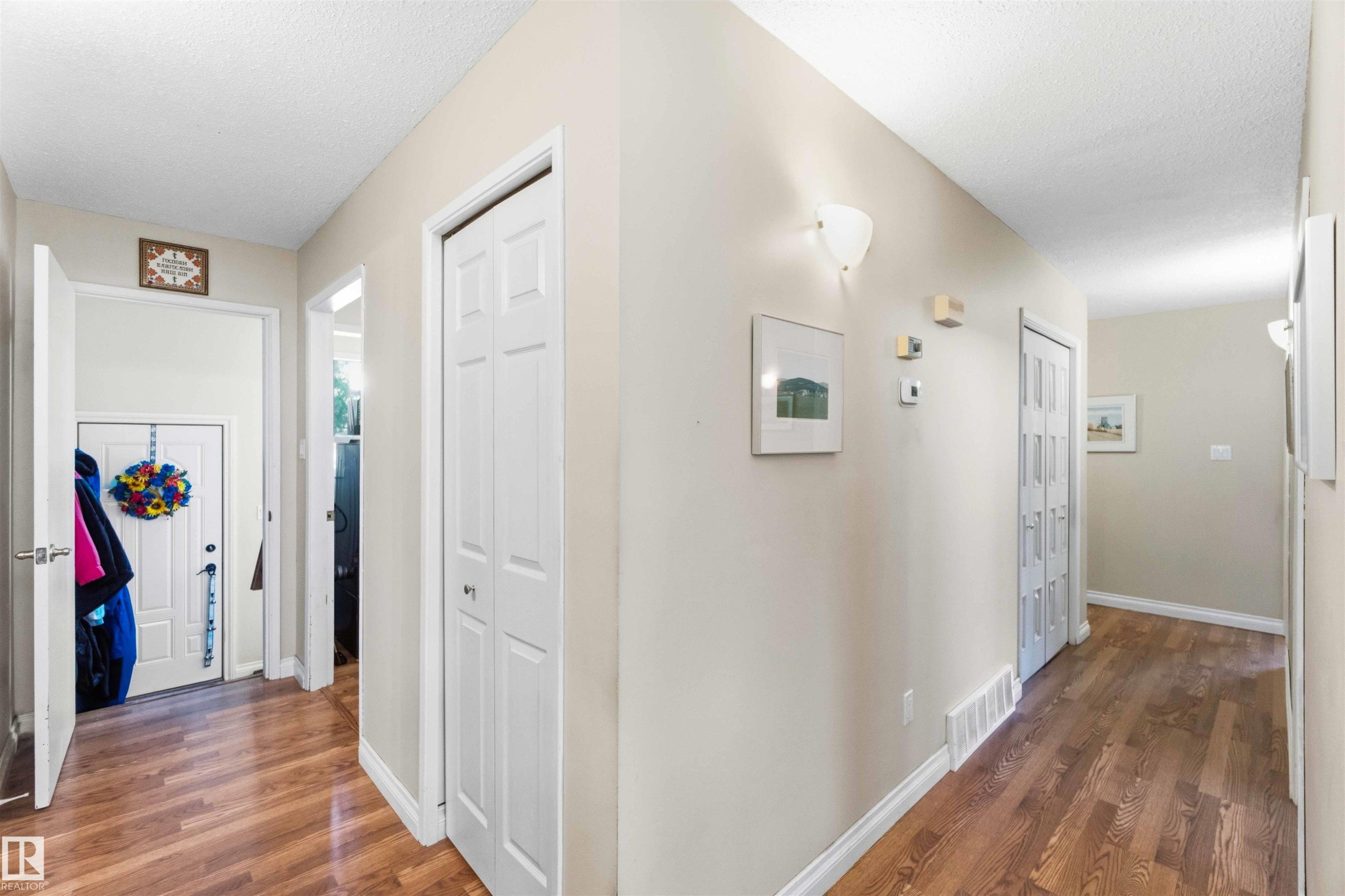 Foyer featuring wood-finish flooring, white trim, and a white six-panel door - 13121 122 Street, Edmonton, AB