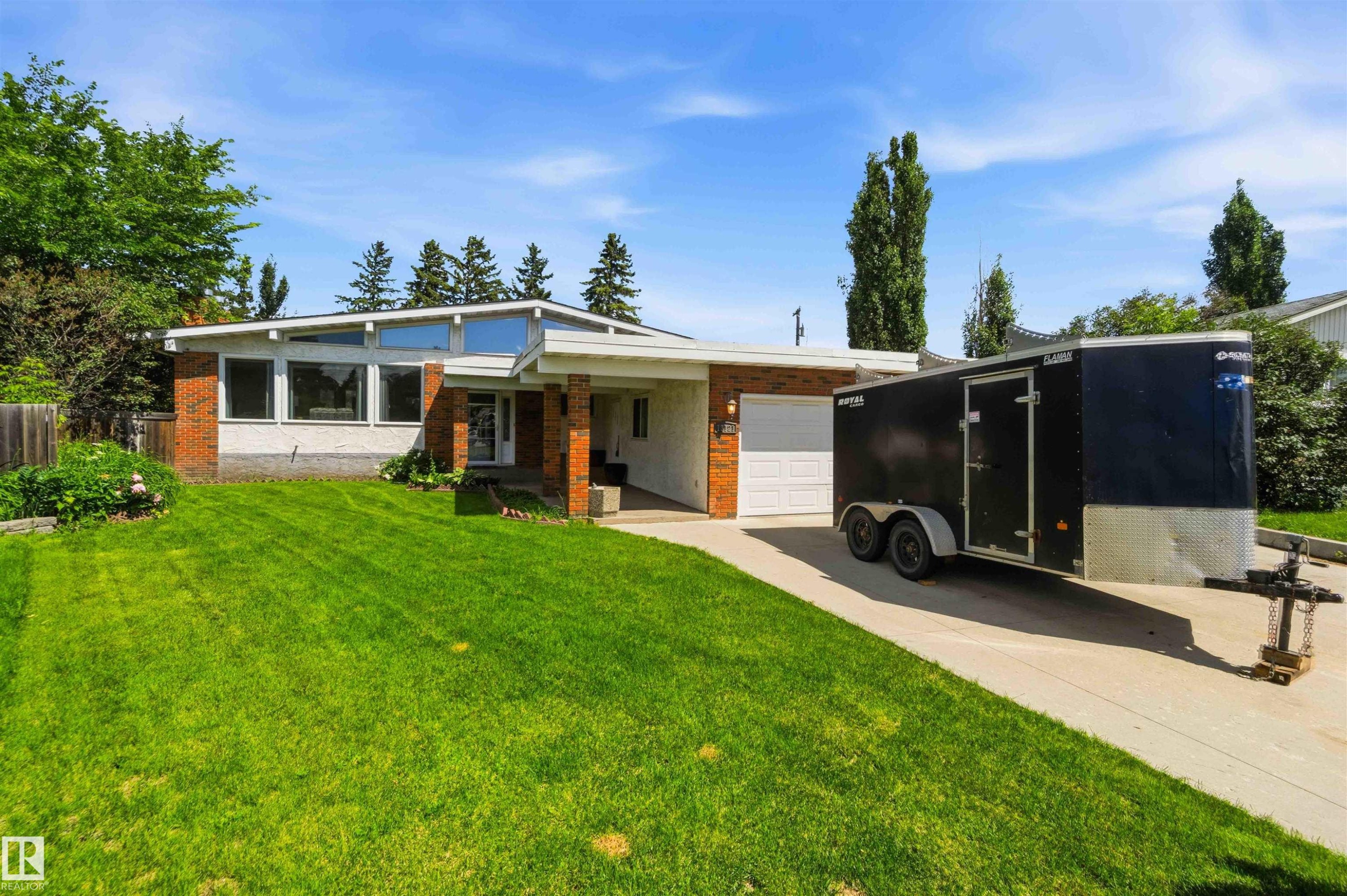 Single-story residence featuring a brick and white facade, an attached single-car garage, large front windows, a peaked roofline, and a concrete driveway - 13121 122 Street, Edmonton, AB