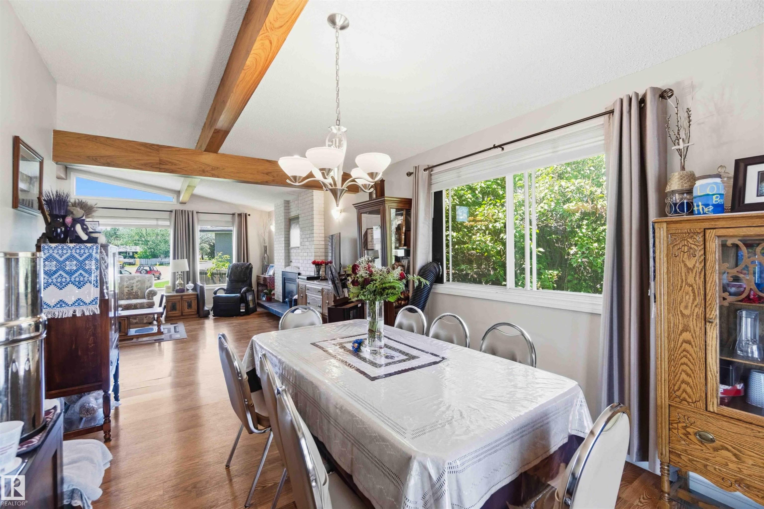 Dining area with wood-finish flooring, a contemporary chandelier, and a large window - 13121 122 Street, Edmonton, AB