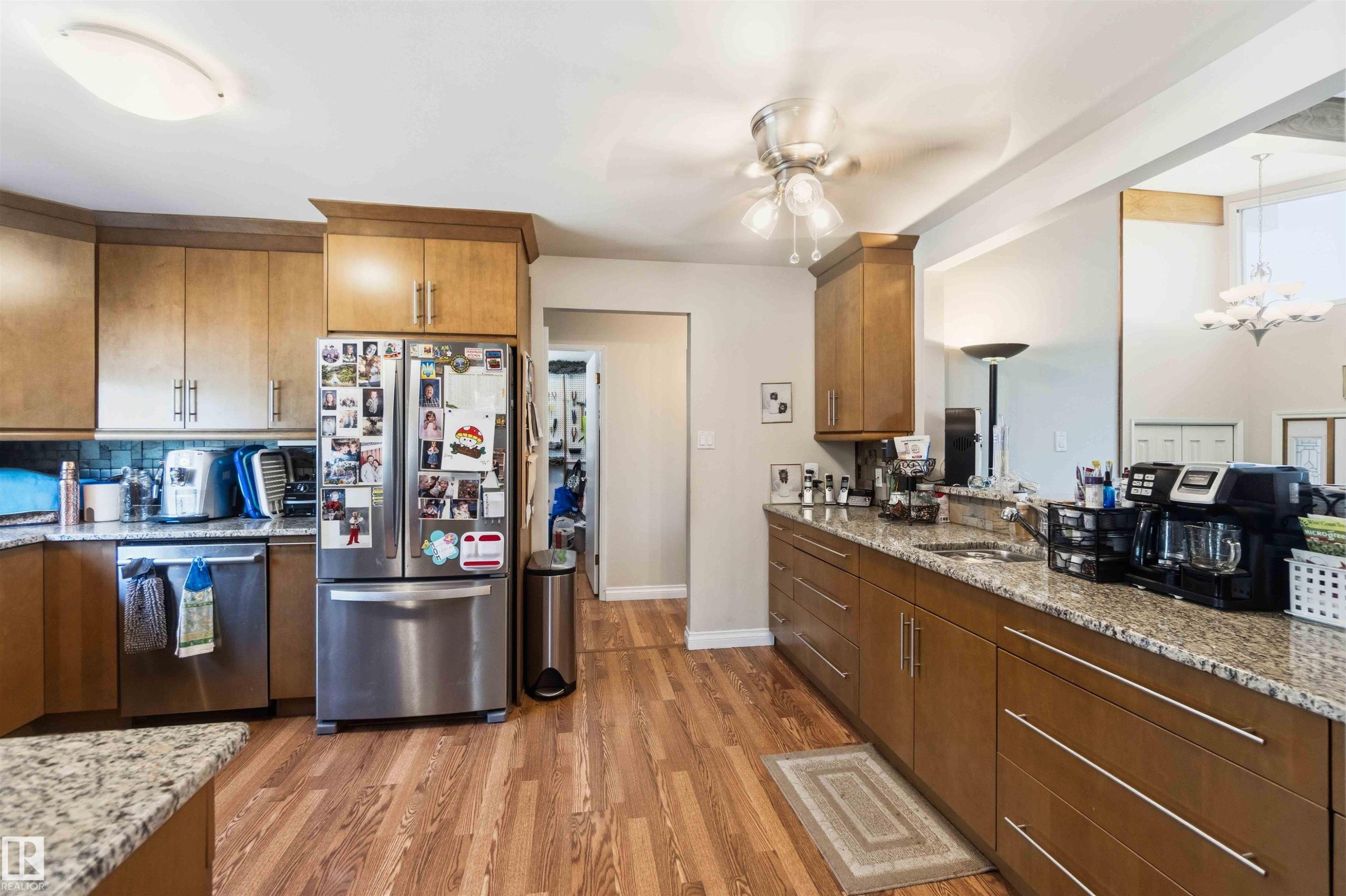 Kitchen featuring wood-finish flooring, light wood cabinetry, stone-finish countertops, and a tile backsplash - 13121 122 Street, Edmonton, AB