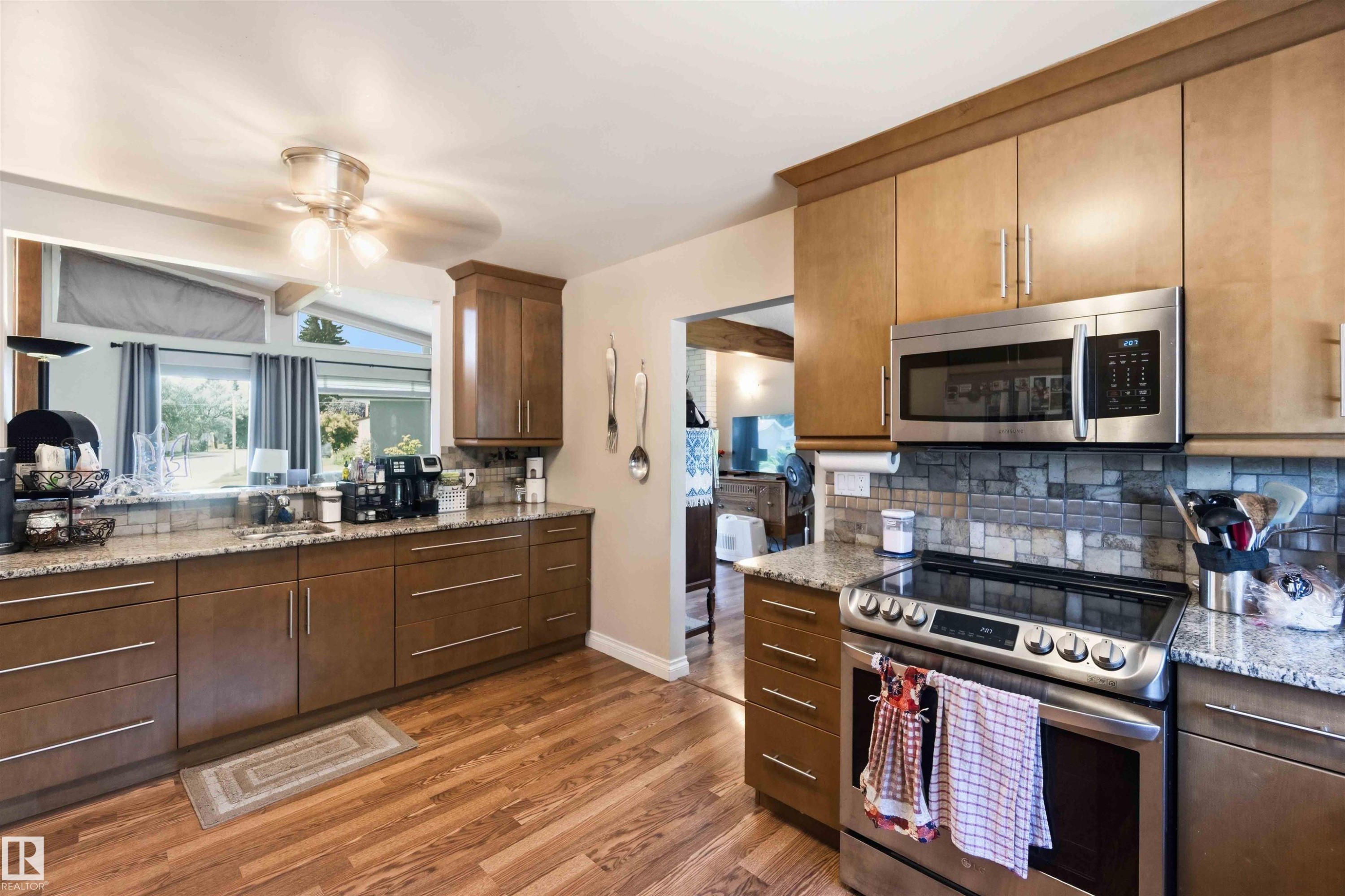 Kitchen featuring wood-finish flooring, granite countertops, and a tiled backsplash - 13121 122 Street, Edmonton, AB