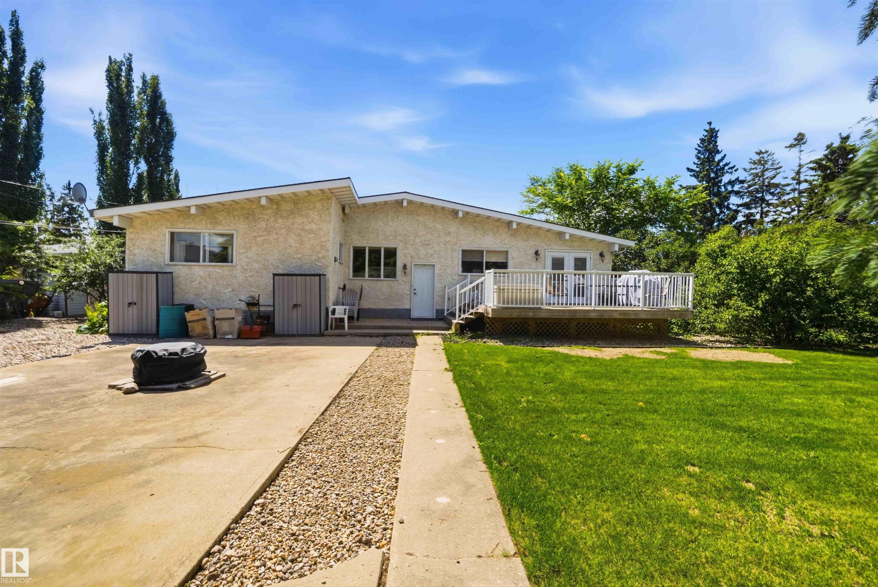Rear exterior with stucco siding and a spacious wooden deck - 13121 122 Street, Edmonton, AB
