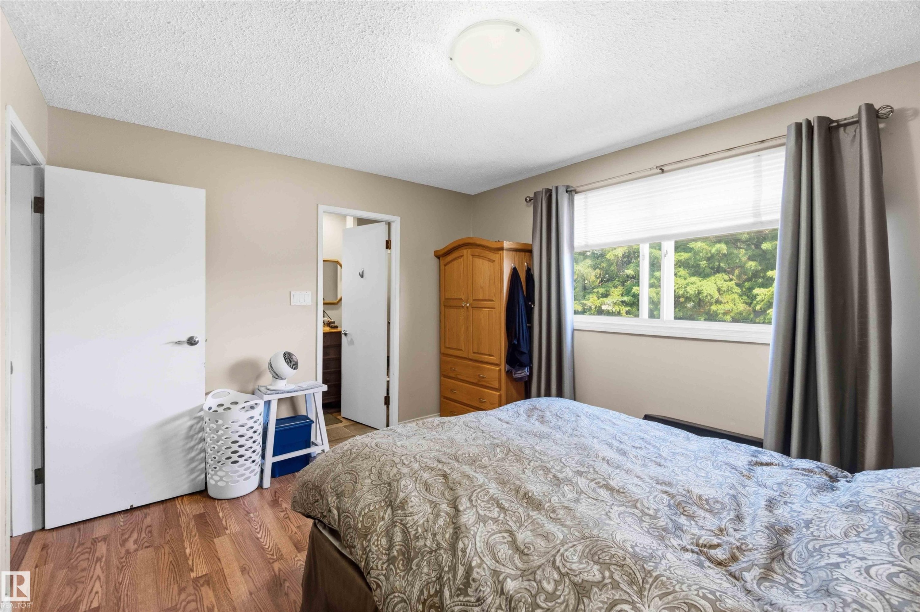 Interior space featuring wood-finish flooring, a window with horizontal blinds, and a flush-mount ceiling light - 13121 122 Street, Edmonton, AB
