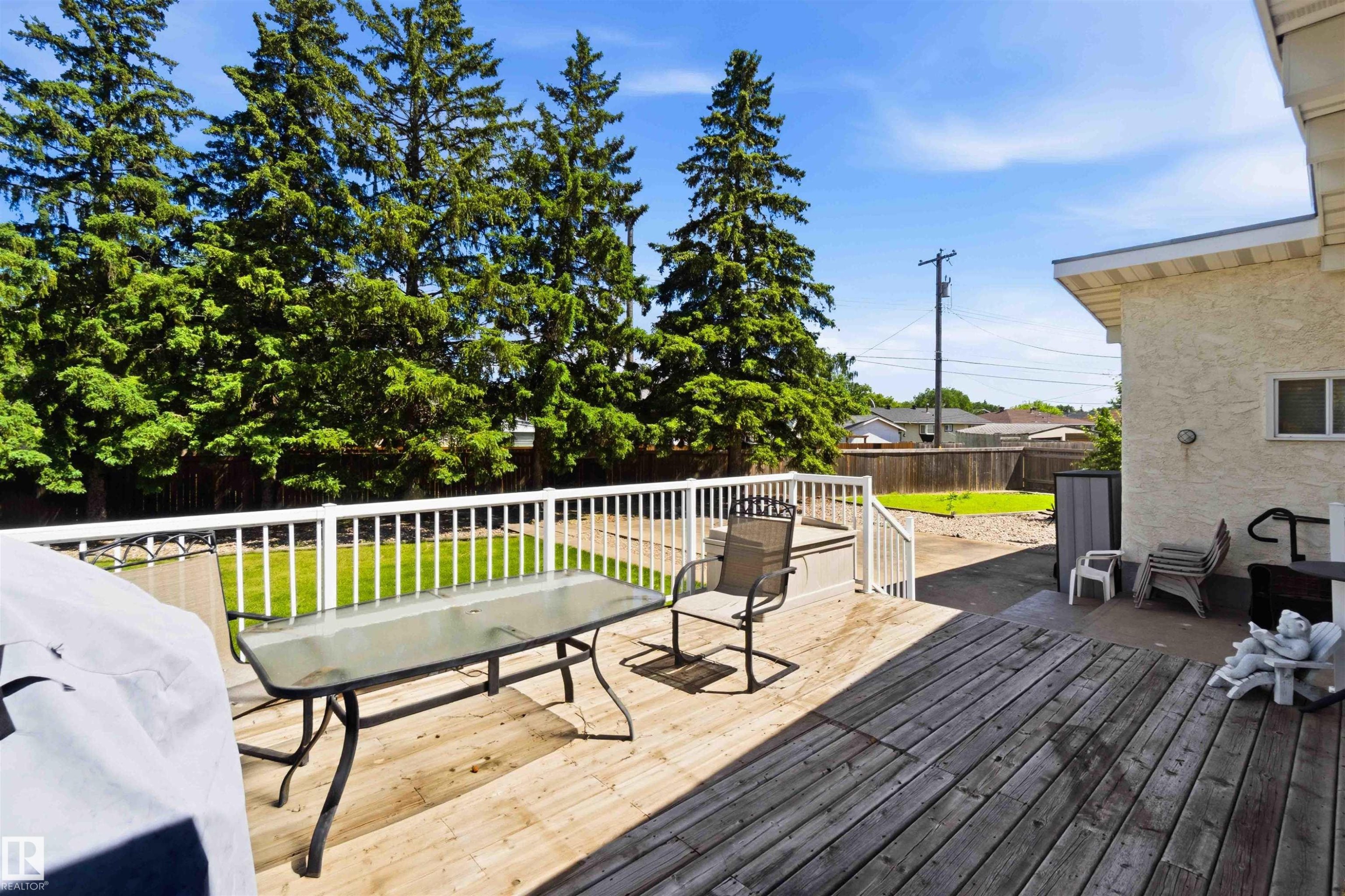 Expansive backyard featuring a large wood deck with white railings, a lower gravel patio, and a grass lawn - 13121 122 Street, Edmonton, AB